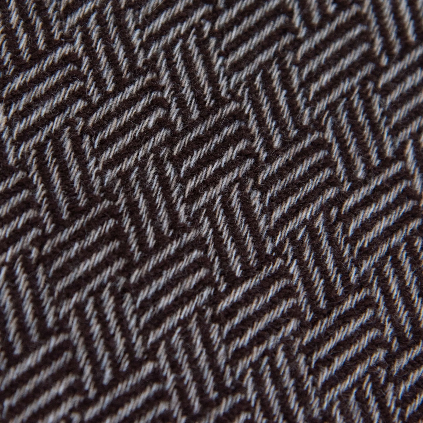 Dettaglio e texture tessuto della Sciarpa in 100% cashmere marrone, Made in Italy, con intramontabile pattern ad intreccio e lavorazione leggera in 3D che accentua la percezione al tatto. Il cashmere di alta qualità offre straordinaria finezza, proprietà termoisolanti e garantisce calore, protezione e leggerezza.