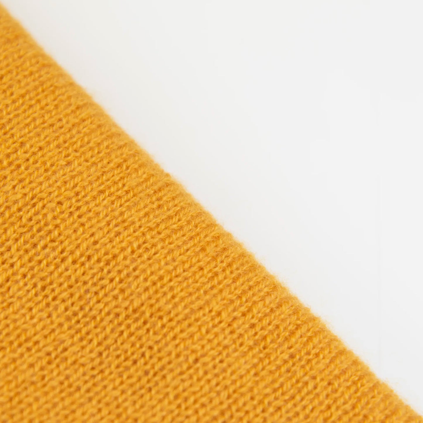 Dettaglio e texture tessuto della mantellina in 100% cashmere gialla, Made in Italy, praticità e comfort con tre diverse vestibilità per ogni esigenza.