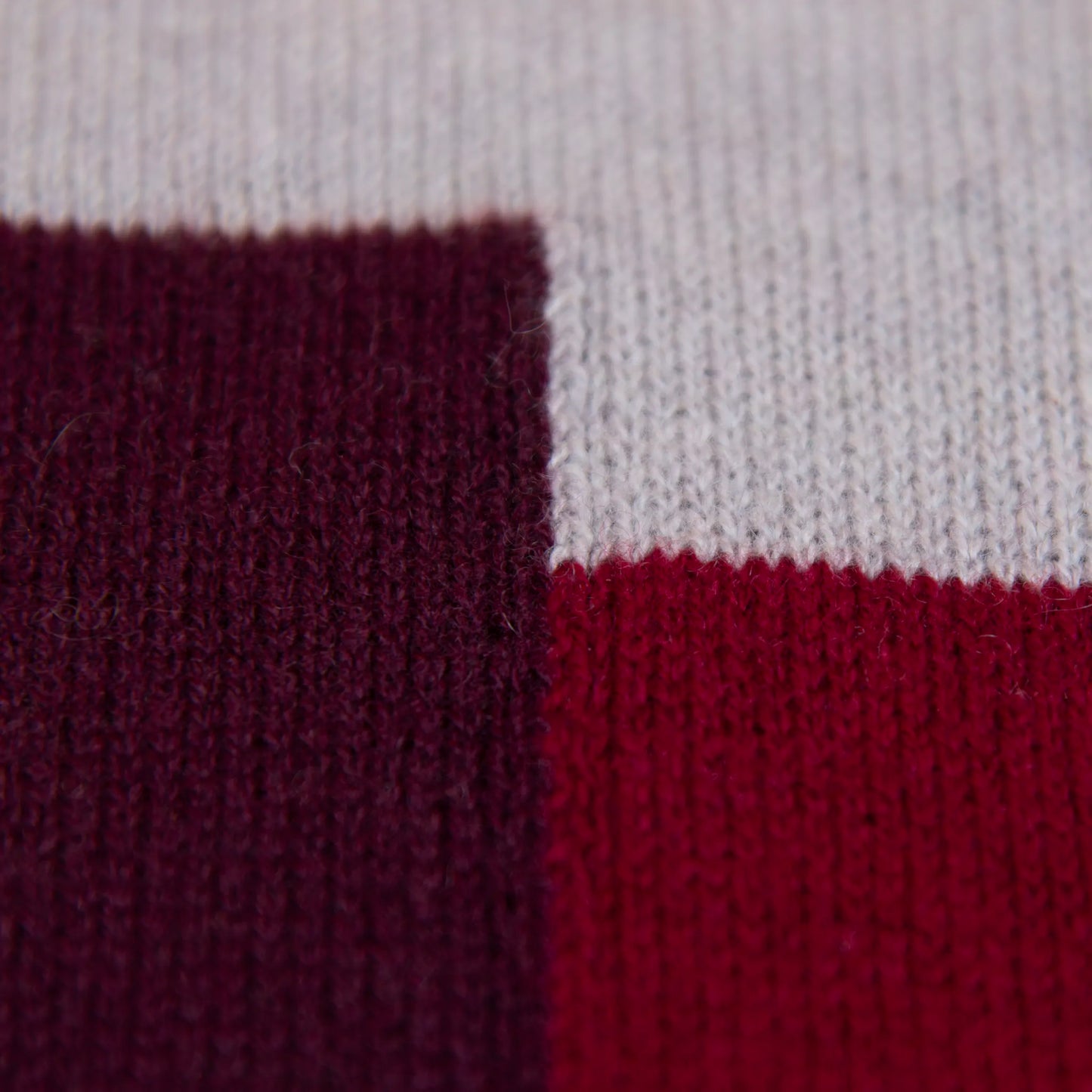Dettaglio e texture tessuto della sciarpa e stola in 100% cashmere bordeaux e rossa, Made in Italy, realizzata su telai antichi. Fibra di cashmere fine e termoisolante, offre calore e leggerezza. Design versatile, perfetta per tutte le stagioni, con accostamento di colori creato da designer esperti.