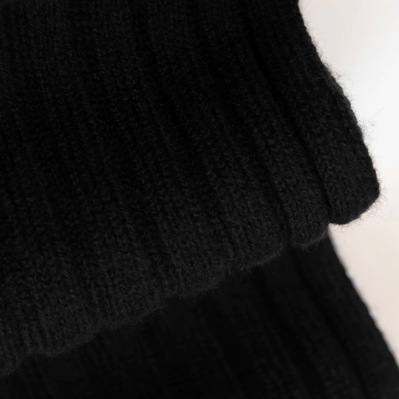 Dettaglio e texture del tessuto della sciarpa in 100% cashmere nera, Made in Italy, con trama artigianale realizzata su antichi telai. La struttura robusta e la durata eccezionale del tessuto offrono calore, comfort e leggerezza. Perfetta per aggiungere un tocco di eleganza a qualsiasi outfit, adatta sia a look casual che sofisticati.