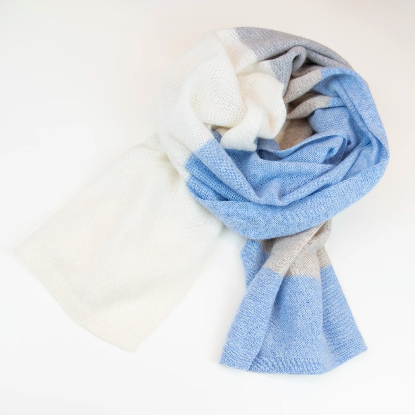 Sciarpa in maglia 100% cashmere celeste, beige e grigia, Made in Italy, realizzata su antichi telai. Grazie alla sua ampiezza, può essere utilizzata anche come stola. La pregiata fibra di cashmere offre un'eccezionale finezza e qualità termoisolanti, assicurando calore, protezione e leggerezza in tutte le stagioni. Un accessorio versatile, frutto della creatività di designer specializzati, che aggiunge eleganza e comfort al tuo look.