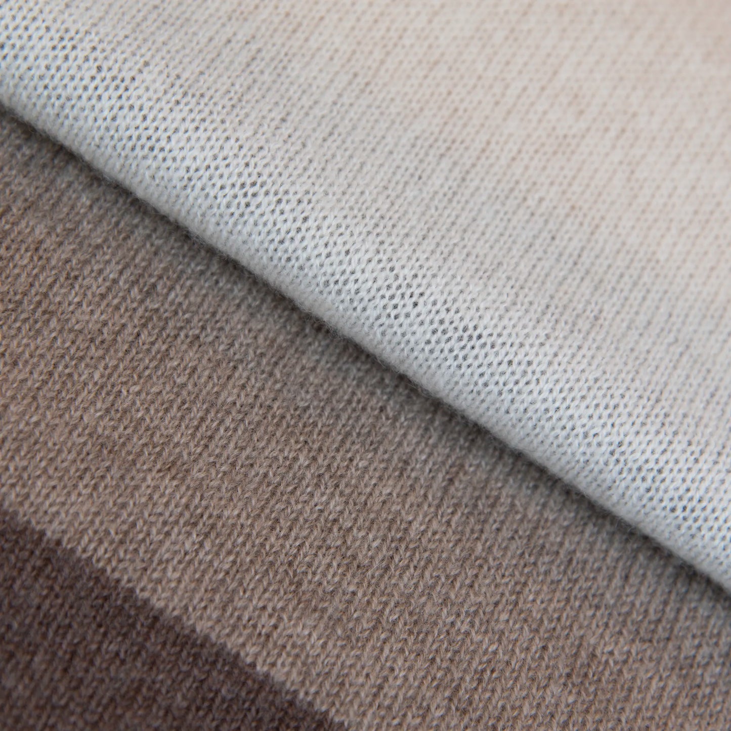 Dettaglio e texture tessuto della sciarpa in maglia 100% cashmere senape, beige e marrone, Made in Italy, realizzata su antichi telai. Grazie alla sua ampiezza, può essere utilizzata anche come stola. La pregiata fibra di cashmere offre un'eccezionale finezza e qualità termoisolanti, assicurando calore, protezione e leggerezza in tutte le stagioni. Un accessorio versatile, frutto della creatività di designer specializzati, che aggiunge eleganza e comfort al tuo look.