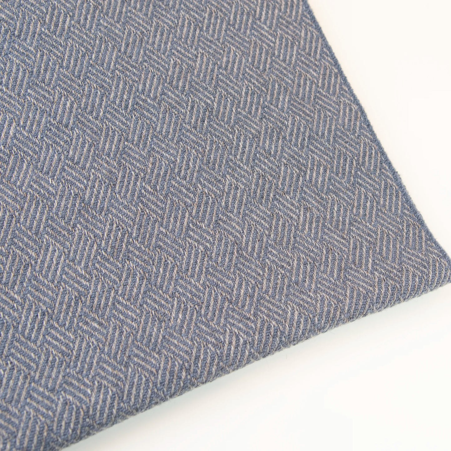 Dettaglio e texture tessuto della Sciarpa in 100% cashmere celeste polvere, Made in Italy, con intramontabile pattern ad intreccio e lavorazione leggera in 3D che accentua la percezione al tatto. Il cashmere di alta qualità offre straordinaria finezza, proprietà termoisolanti e garantisce calore, protezione e leggerezza.