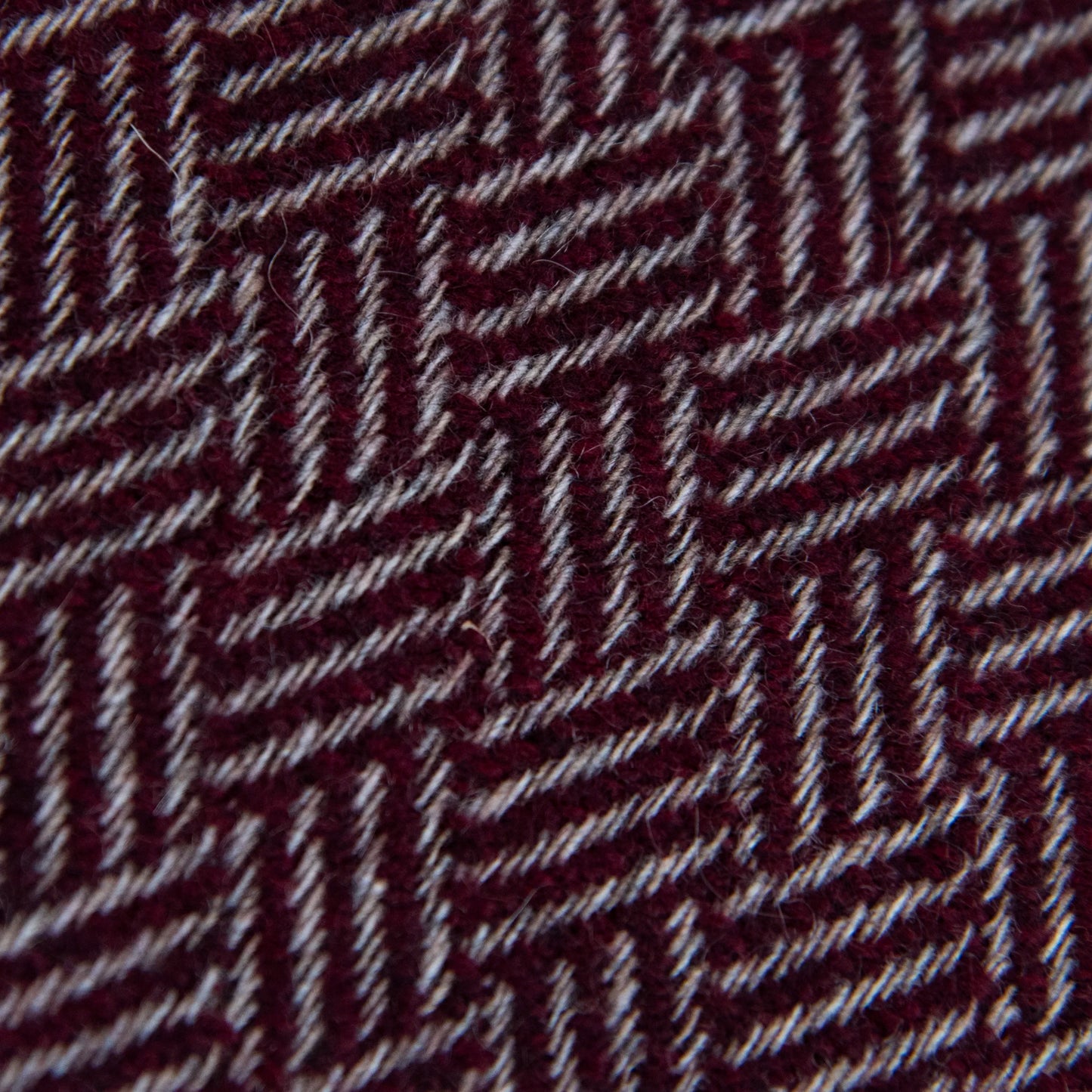 Dettaglio e texture tessuto della Sciarpa in 100% cashmere bordeaux, Made in Italy, con intramontabile pattern ad intreccio e lavorazione leggera in 3D che accentua la percezione al tatto. Il cashmere di alta qualità offre straordinaria finezza, proprietà termoisolanti e garantisce calore, protezione e leggerezza.