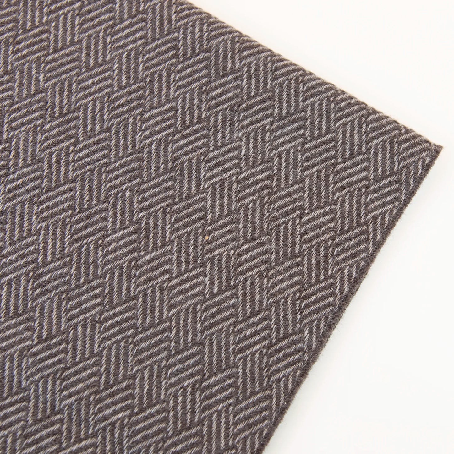 Dettaglio e texture tessuto della Sciarpa in 100% cashmere marrone, Made in Italy, con intramontabile pattern ad intreccio e lavorazione leggera in 3D che accentua la percezione al tatto. Il cashmere di alta qualità offre straordinaria finezza, proprietà termoisolanti e garantisce calore, protezione e leggerezza.