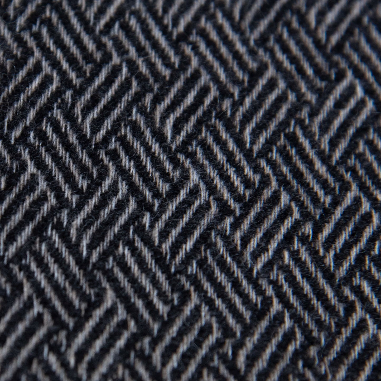 Dettaglio e texture tessuto della Sciarpa in 100% cashmere nera, Made in Italy, con intramontabile pattern ad intreccio e lavorazione leggera in 3D che accentua la percezione al tatto. Il cashmere di alta qualità offre straordinaria finezza, proprietà termoisolanti e garantisce calore, protezione e leggerezza.