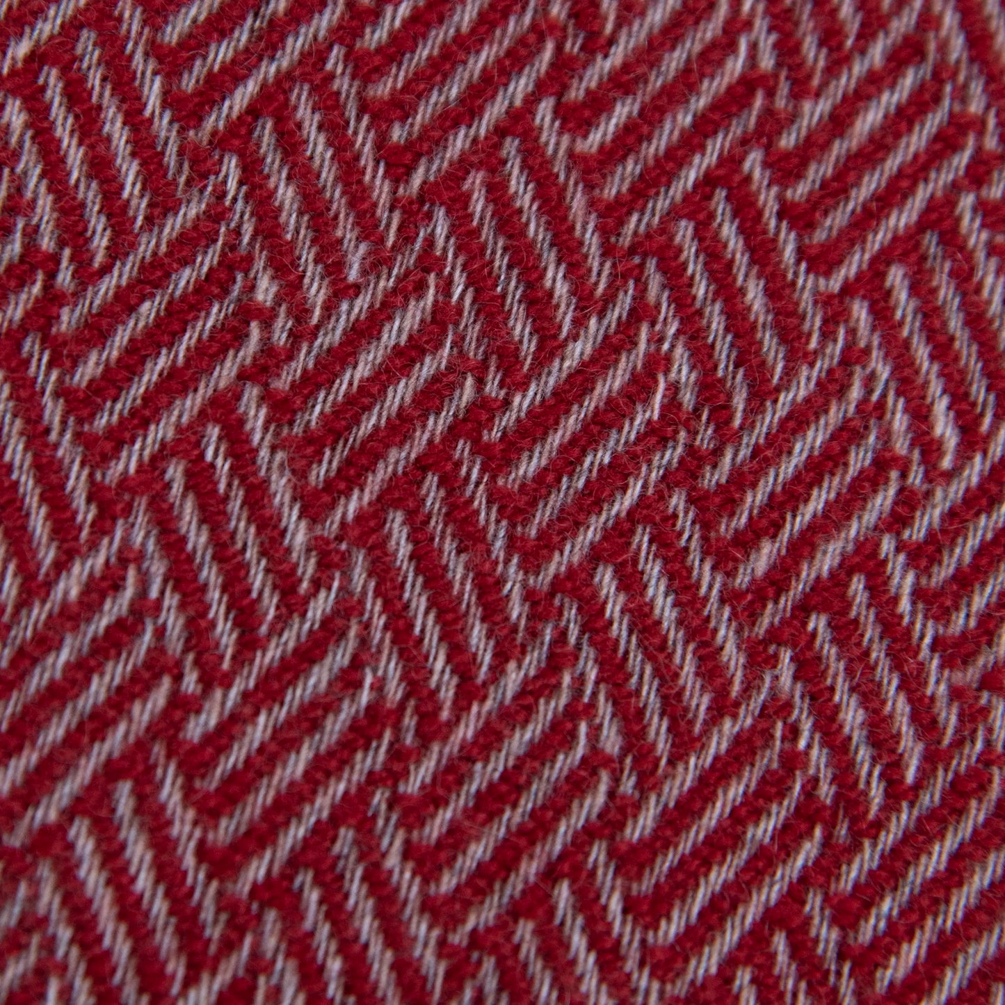 Dettaglio e texture tessuto della Sciarpa in 100% cashmere rossa, Made in Italy, con intramontabile pattern ad intreccio e lavorazione leggera in 3D che accentua la percezione al tatto. Il cashmere di alta qualità offre straordinaria finezza, proprietà termoisolanti e garantisce calore, protezione e leggerezza.