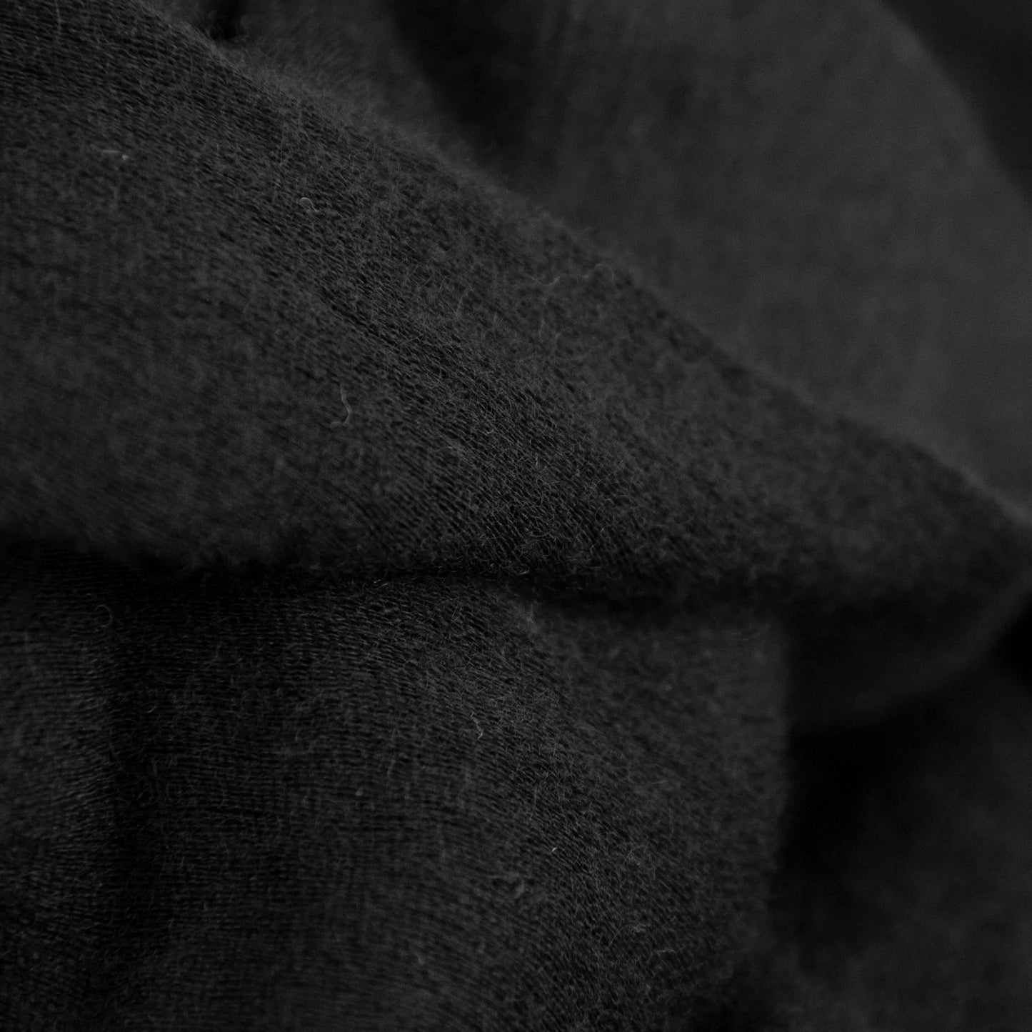 Dettagli e texture tessuto della pashmina nera in 100% cashmere Made in Italy, tessitura a jersey, leggera e vaporosa, perfetta come sciarpa o stola per tutte le stagioni.