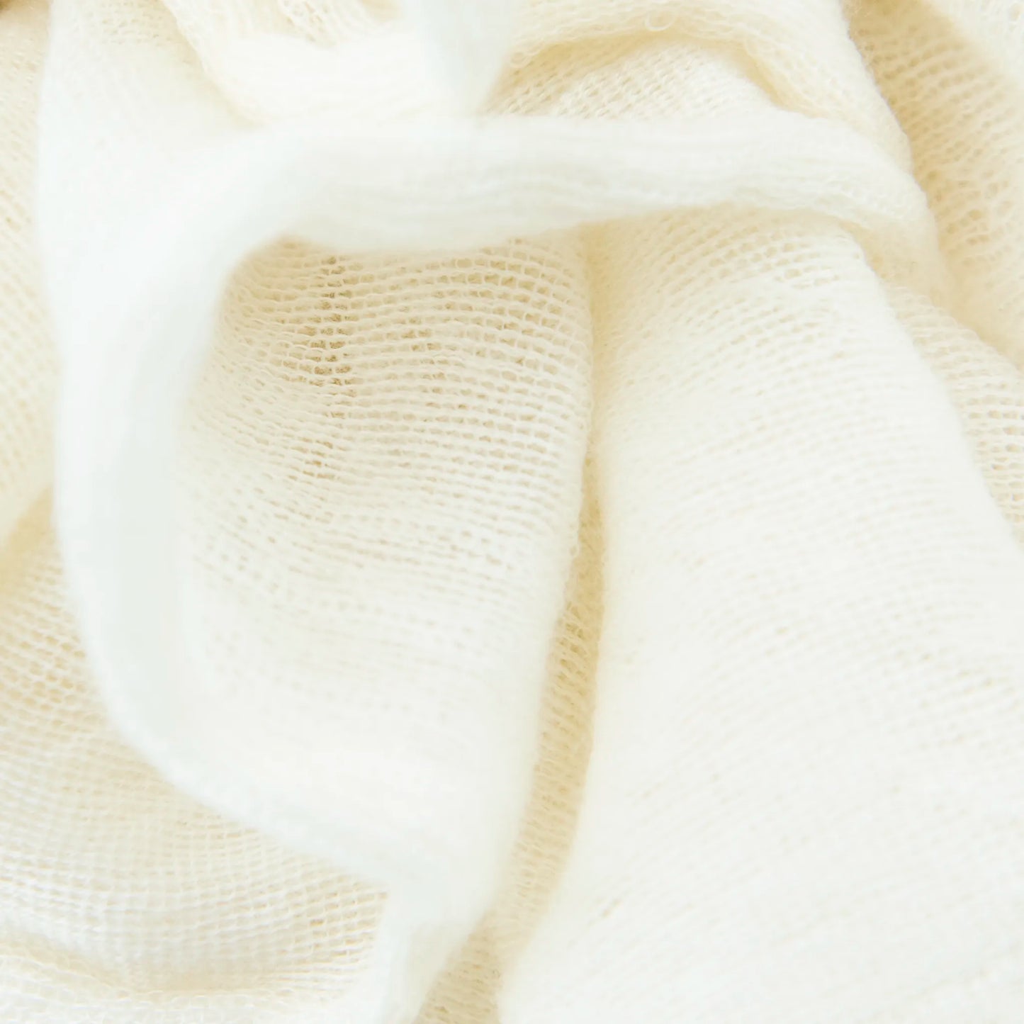 Dettagli e texture tessuto della pashmina panna in 100% cashmere Made in Italy, tessitura a jersey, leggera e vaporosa, perfetta come sciarpa o stola per tutte le stagioni.