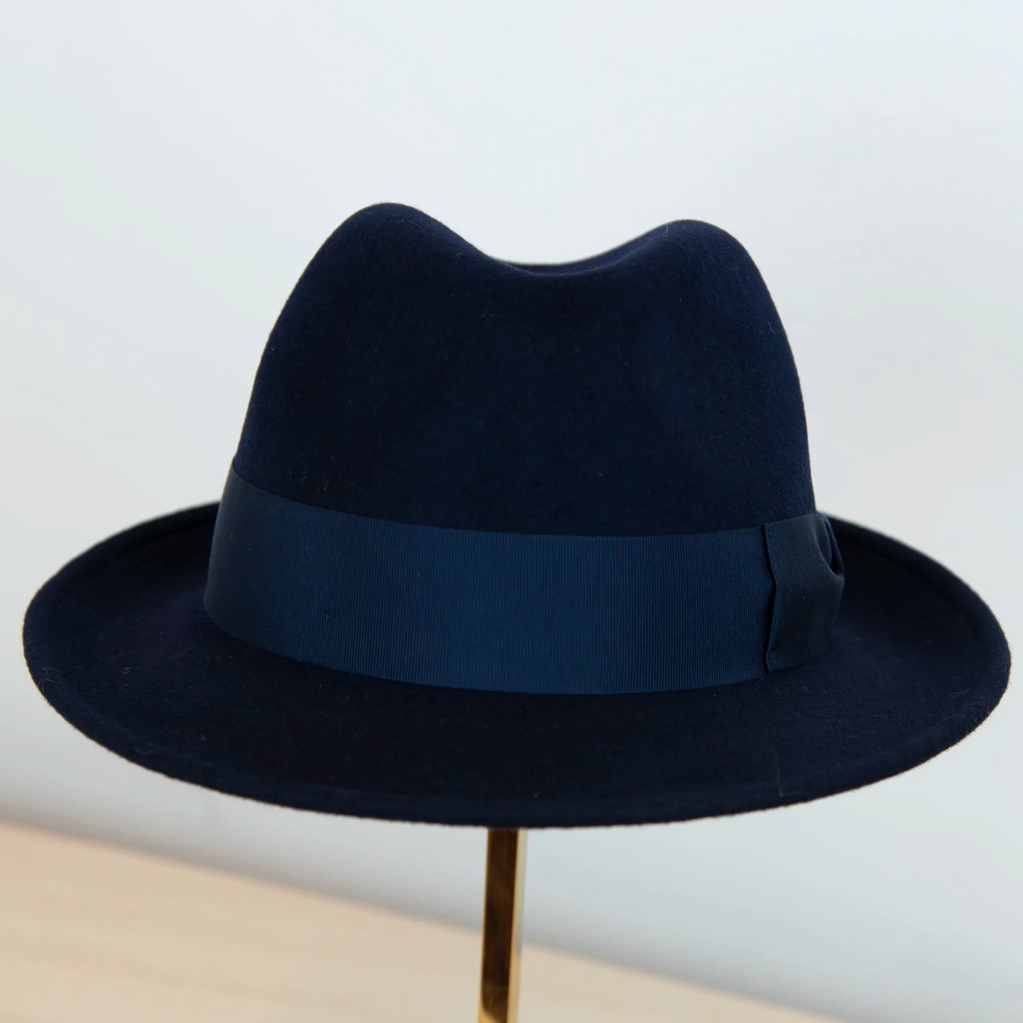 Dettaglio del cappello in feltro di lana blu, Made in Italy, ispirato a Humphrey Bogart. Falda media 5,5 cm rialzata sul retro, cupola 11,5 cm, cinta in gros-grain 4 cm blu. Eleganza senza tempo.