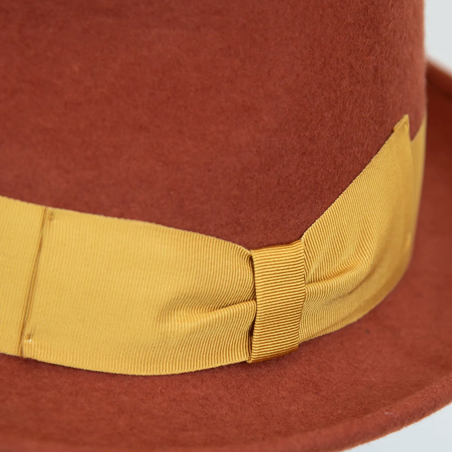Dettaglio cinta e tessuto del cappello in feltro di lana coccio, Made in Italy, falda corta 5 cm e cinta in gros-grain gialla. Parte della Collezione Emporio San Felice, elegante e versatile per ogni occasione.