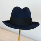 Cappello in 100% lapin blu, Made in Italy, realizzato su antiche forme in legno. Ispirato ai primi del '900, con cupola alta 13,5 cm e cinta nera di 5 cm per uno stile iconico.