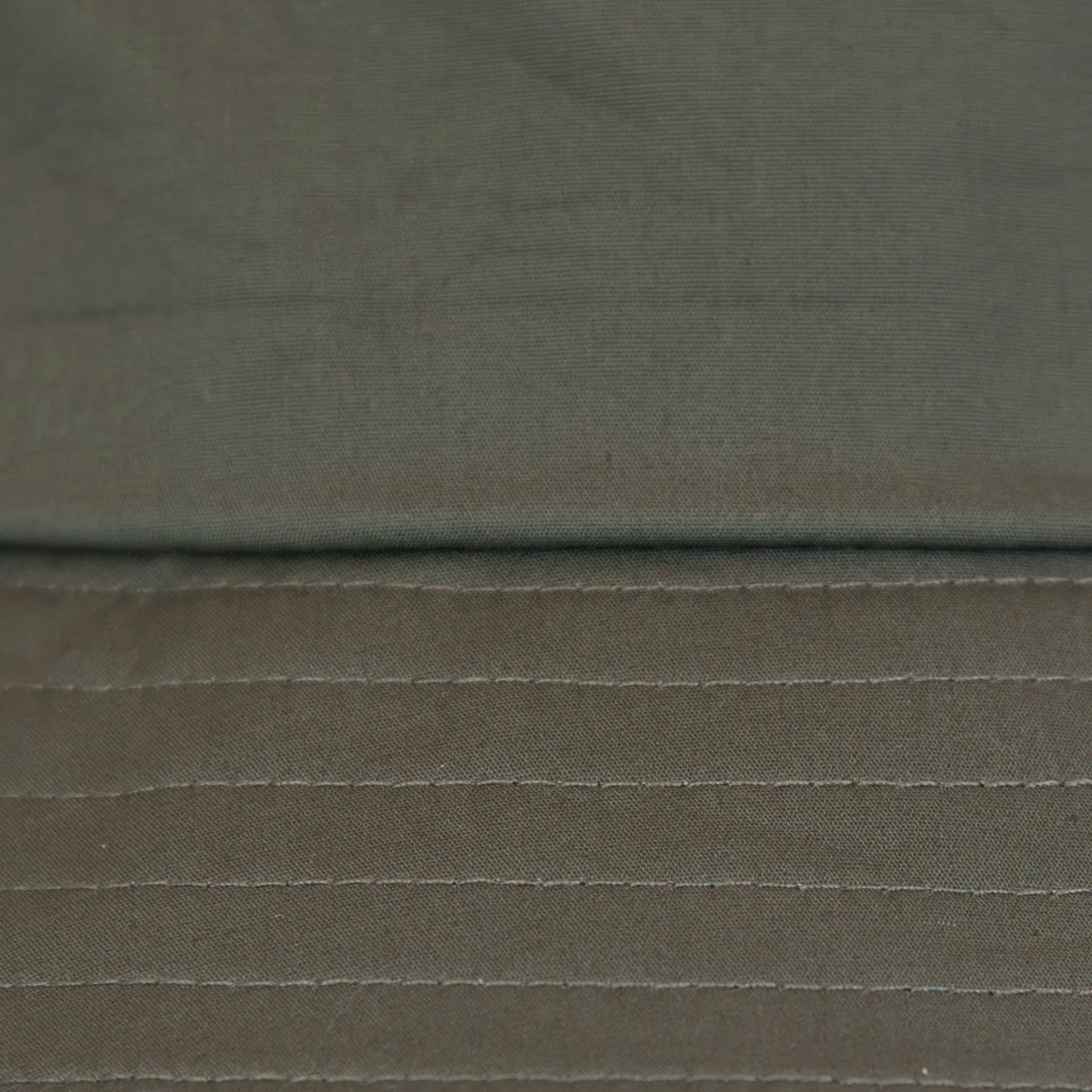 Dettaglio tessuto del cappello antipioggia bucket verde con cuciture termosaldate, impermeabile, facile da conservare in borsa o tasca mantenendo la forma. Made in Italy