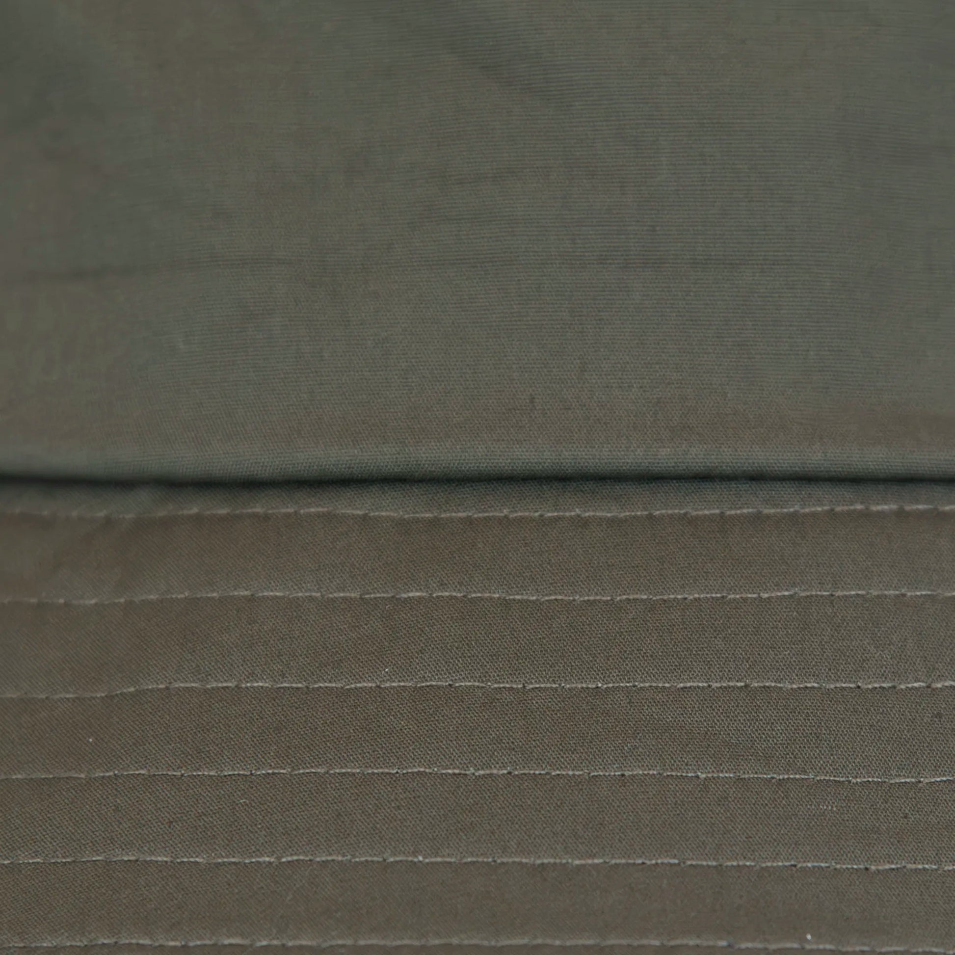 Dettaglio tessuto del cappello antipioggia bucket verde con cuciture termosaldate, impermeabile, facile da conservare in borsa o tasca mantenendo la forma. Made in Italy