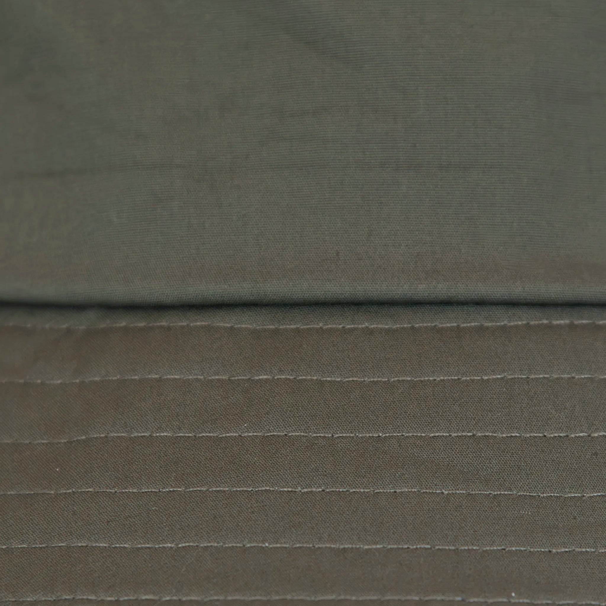 Dettaglio tessuto del cappello antipioggia bucket verde con cuciture termosaldate, impermeabile, facile da conservare in borsa o tasca mantenendo la forma. Made in Italy