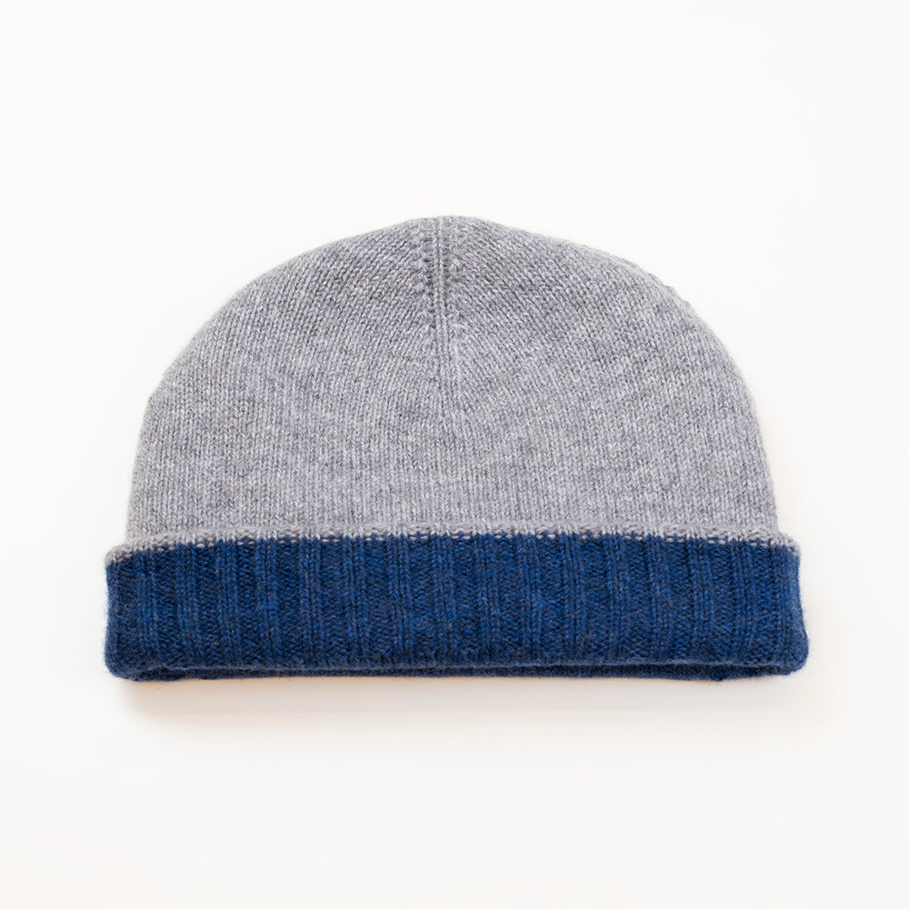 Cuffia doubleface grigio e blu in 100% Cashmere, Made in Italy. Pratica e versatile, può essere indossata con o senza risvolto. Trama rasata e pregiata manifattura per una vestibilità confortevole e di qualità.
