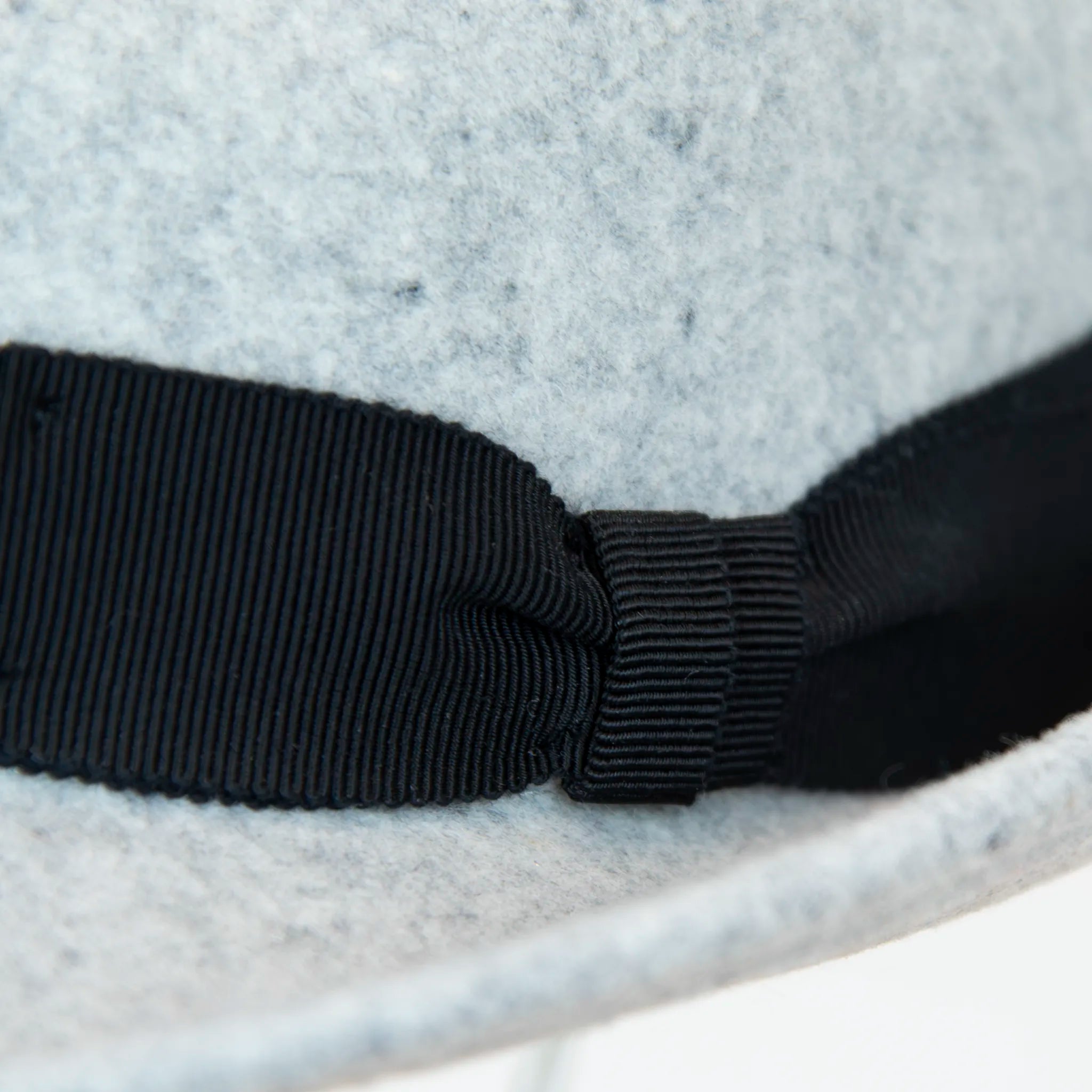 Dettaglio nastro e tessuto del cappello in feltro di lana grigio chiaro, Made in Italy, con tesa corta rialzata sul retro e nastro in gros-grain 3 cm nero. Realizzato da un antico cappellificio italiano, unisce tradizione e stile.