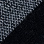Dettaglio e texture tessuto della mantellina aperta nera e grigia in misto cashmere Made in Italy, versatile e confortevole, con due diverse vestibilità per adattarsi a ogni stile e occasione.