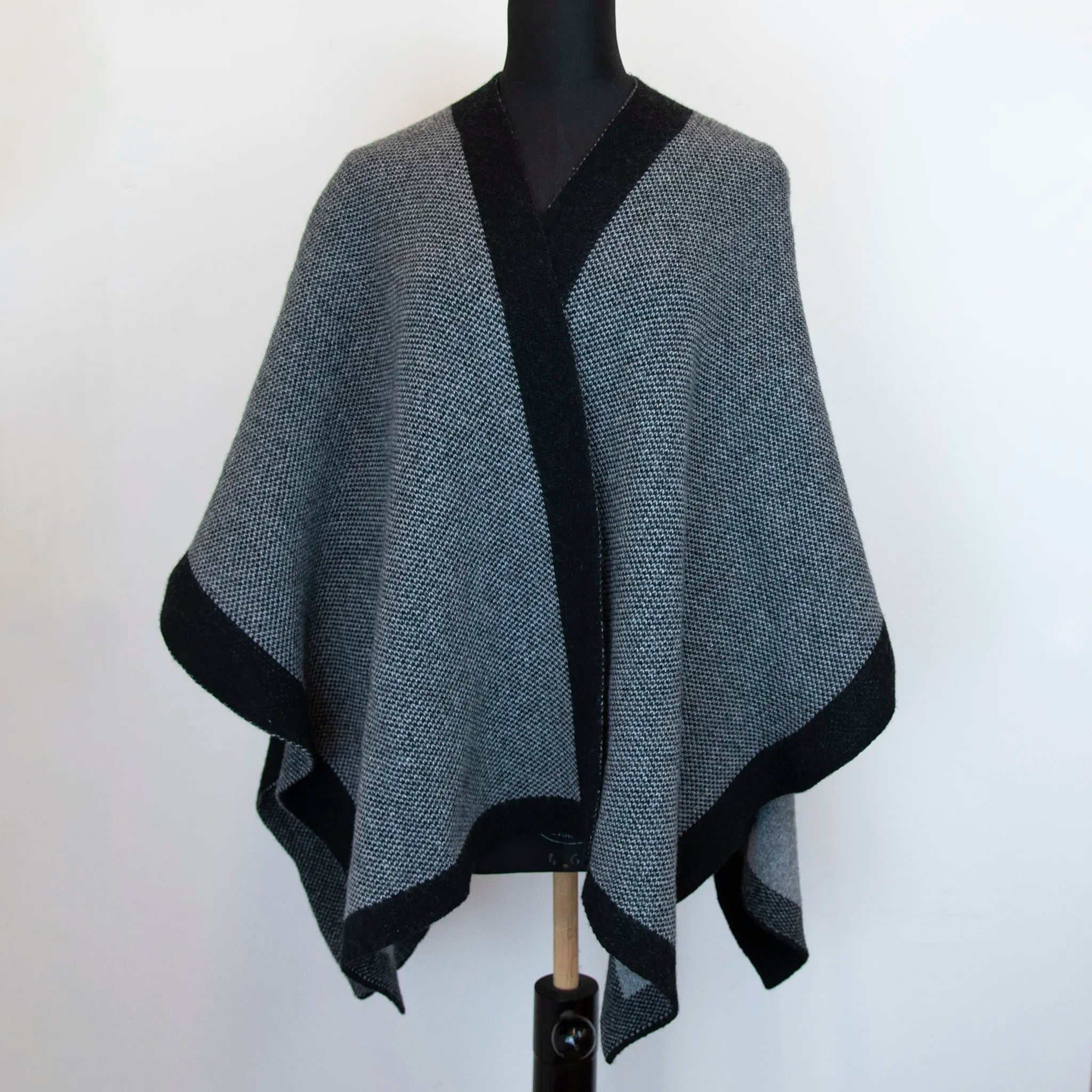 Mantellina aperta nera e grigia in misto cashmere Made in Italy, versatile e confortevole, con due diverse vestibilità per adattarsi a ogni stile e occasione.