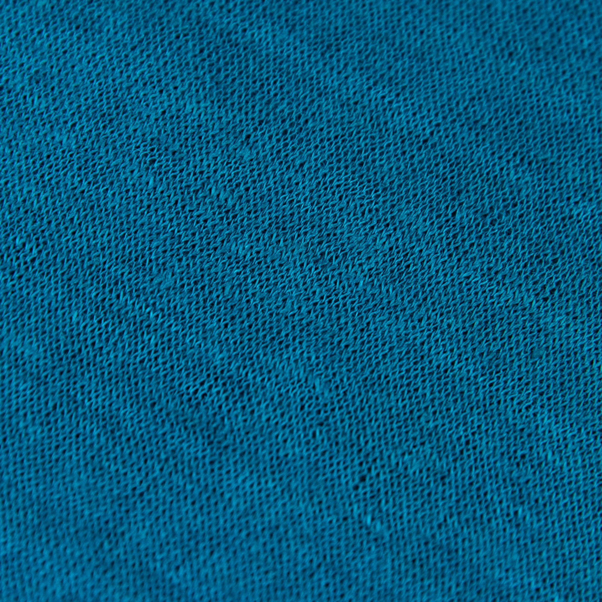 Dettagli e texture tessuto della mantellina in 100% Lino turchese, Made in Italy, praticità e comfort con tre diverse vestibilità per ogni esigenza.