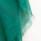 Dettagli e texture della Pashmina in cashmere e modal verde a tessitura twill, pregiata manifattura Made in Italy, sottile ed elegante adatta a ogni stagione.