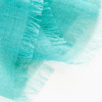 Dettagli e texture della Pashmina in cashmere e modal verde a tessitura twill, pregiata manifattura Made in Italy, sottile ed elegante adatta a ogni stagione.