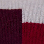 Dettaglio e texture tessuto della sciarpa e stola in 100% cashmere bordeaux e rossa, Made in Italy, realizzata su telai antichi. Fibra di cashmere fine e termoisolante, offre calore e leggerezza. Design versatile, perfetta per tutte le stagioni, con accostamento di colori creato da designer esperti.