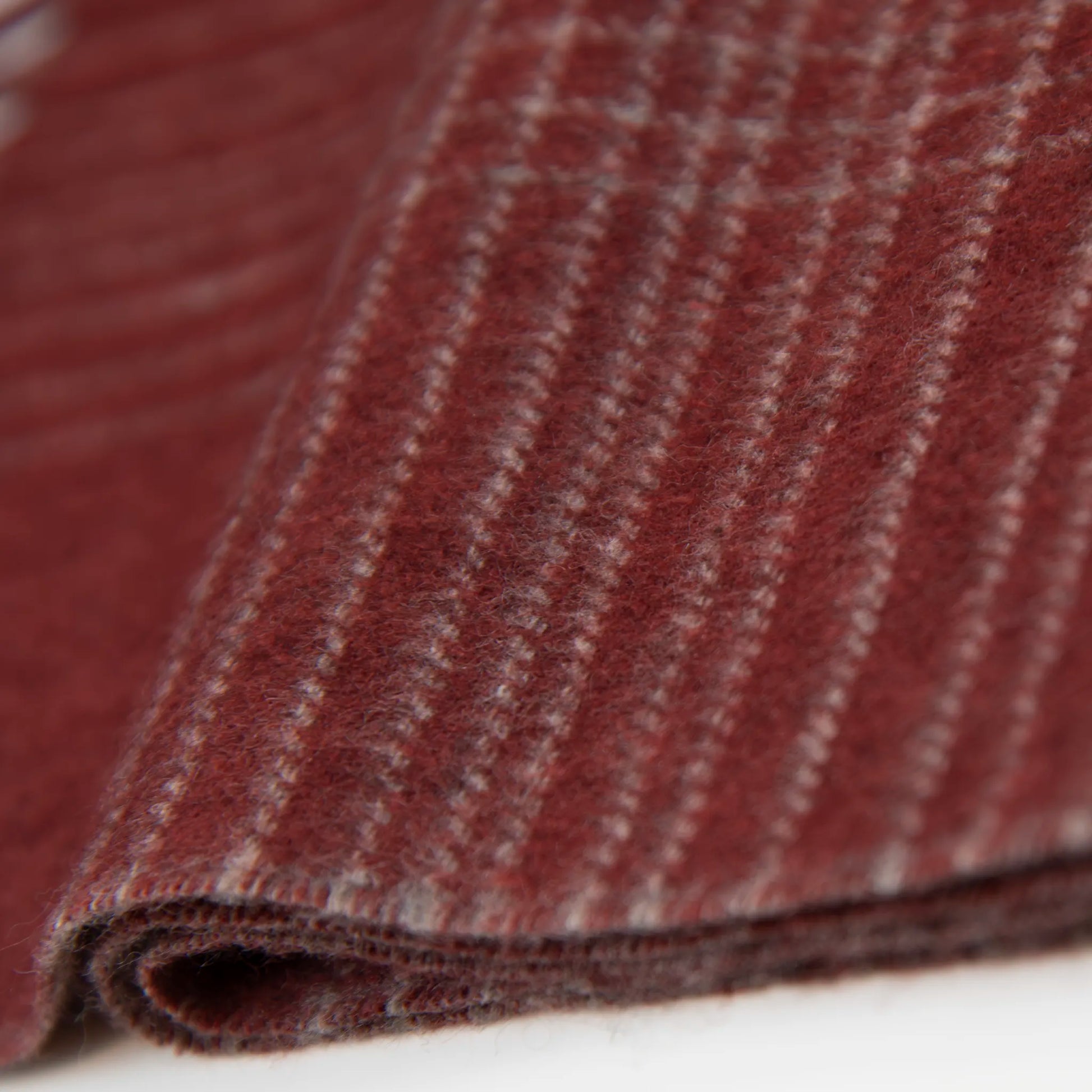 Dettaglio e texture tessuto della sciarpa in cashmere e seta bordeaux, Made in Italy, pattern lineare e tonalità calde. Design raffinato, facile da abbinare. Morbida, confortevole e leggera, per ogni occasione.