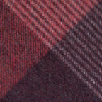 Dettaglio e texture tessuto della sciarpa in cashmere e seta, rossa e bordeaux, Made in Italy, con pattern geometrico a quadri e scacchi in tonalità calde. Il design equilibrato e raffinato, unito alla combinazione cromatica, la rende facilmente abbinabile in ogni occasione. Morbida e confortevole, questa sciarpa offre calore e leggerezza. Un accessorio versatile, frutto della creatività di designer specializzati, perfetto per aggiungere un tocco elegante a qualsiasi look.