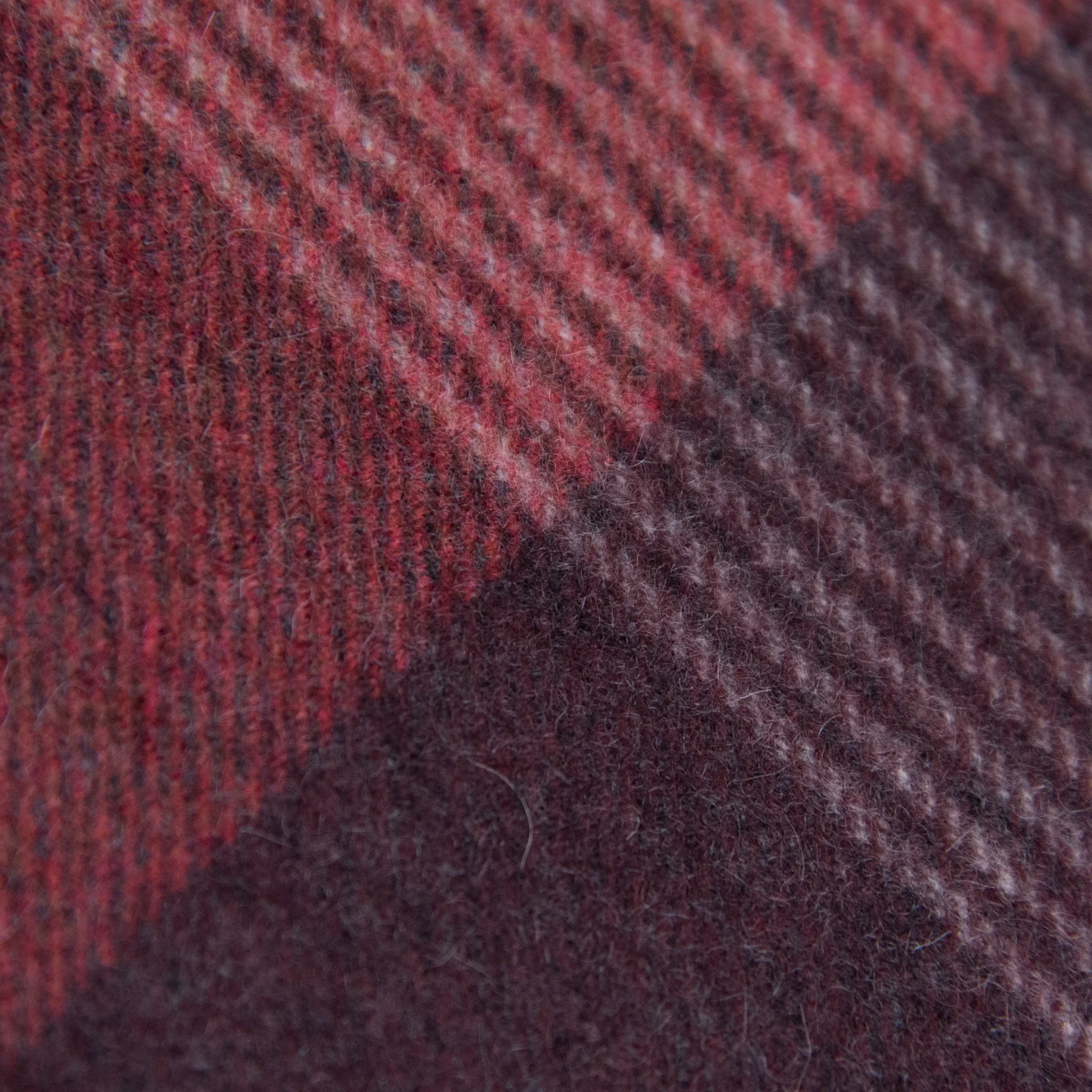 Dettaglio e texture tessuto della sciarpa in cashmere e seta, rossa e bordeaux, Made in Italy, con pattern geometrico a quadri e scacchi in tonalità calde. Il design equilibrato e raffinato, unito alla combinazione cromatica, la rende facilmente abbinabile in ogni occasione. Morbida e confortevole, questa sciarpa offre calore e leggerezza. Un accessorio versatile, frutto della creatività di designer specializzati, perfetto per aggiungere un tocco elegante a qualsiasi look.