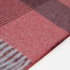 Dettaglio e texture tessuto della sciarpa in cashmere e seta, rossa e bordeaux, Made in Italy, con pattern geometrico a quadri e scacchi in tonalità calde. Il design equilibrato e raffinato, unito alla combinazione cromatica, la rende facilmente abbinabile in ogni occasione. Morbida e confortevole, questa sciarpa offre calore e leggerezza. Un accessorio versatile, frutto della creatività di designer specializzati, perfetto per aggiungere un tocco elegante a qualsiasi look.