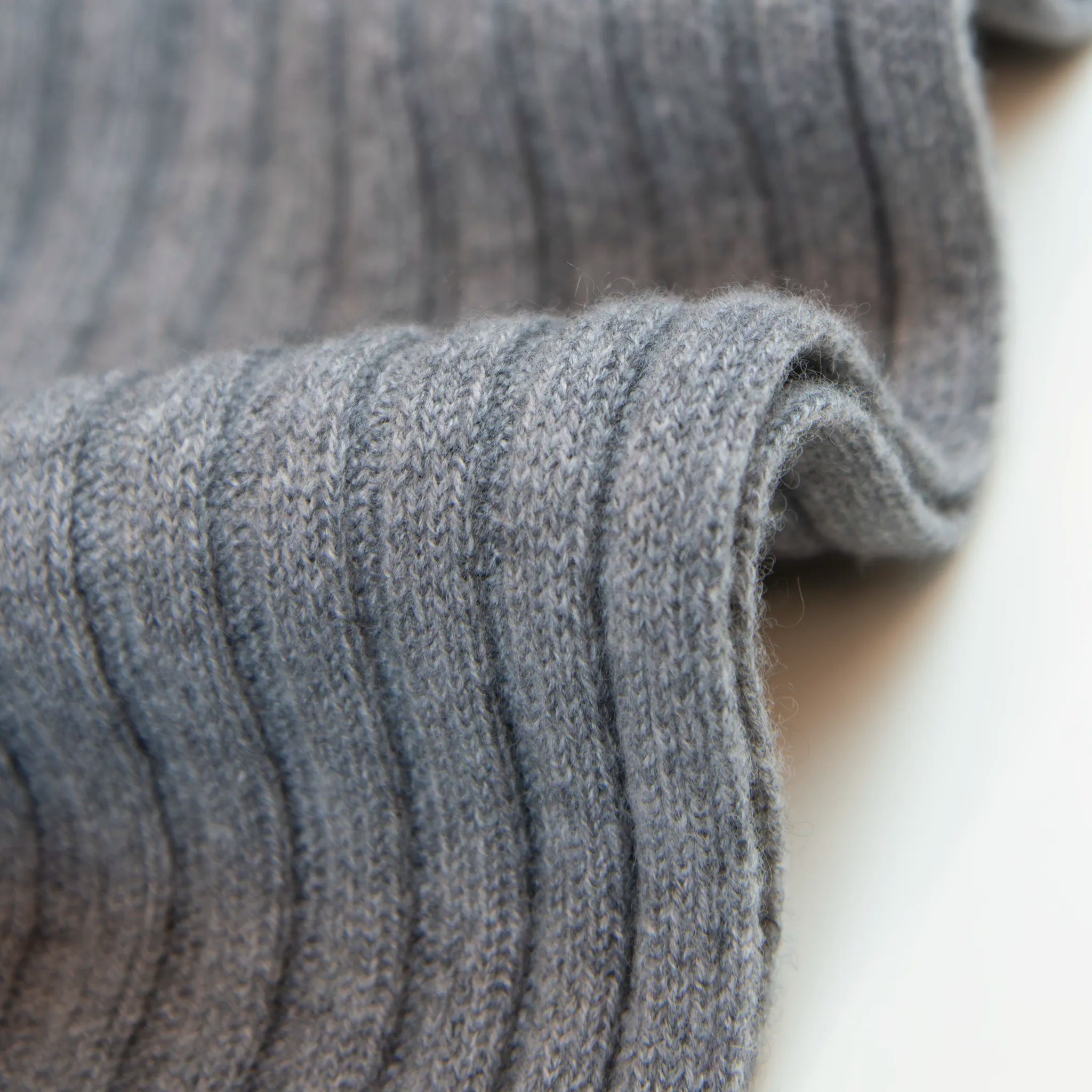 Dettaglio e texture del tessuto della sciarpa in 100% cashmere grigia, Made in Italy, con trama artigianale realizzata su antichi telai. La struttura robusta e la durata eccezionale del tessuto offrono calore, comfort e leggerezza. Perfetta per aggiungere un tocco di eleganza a qualsiasi outfit, adatta sia a look casual che sofisticati.