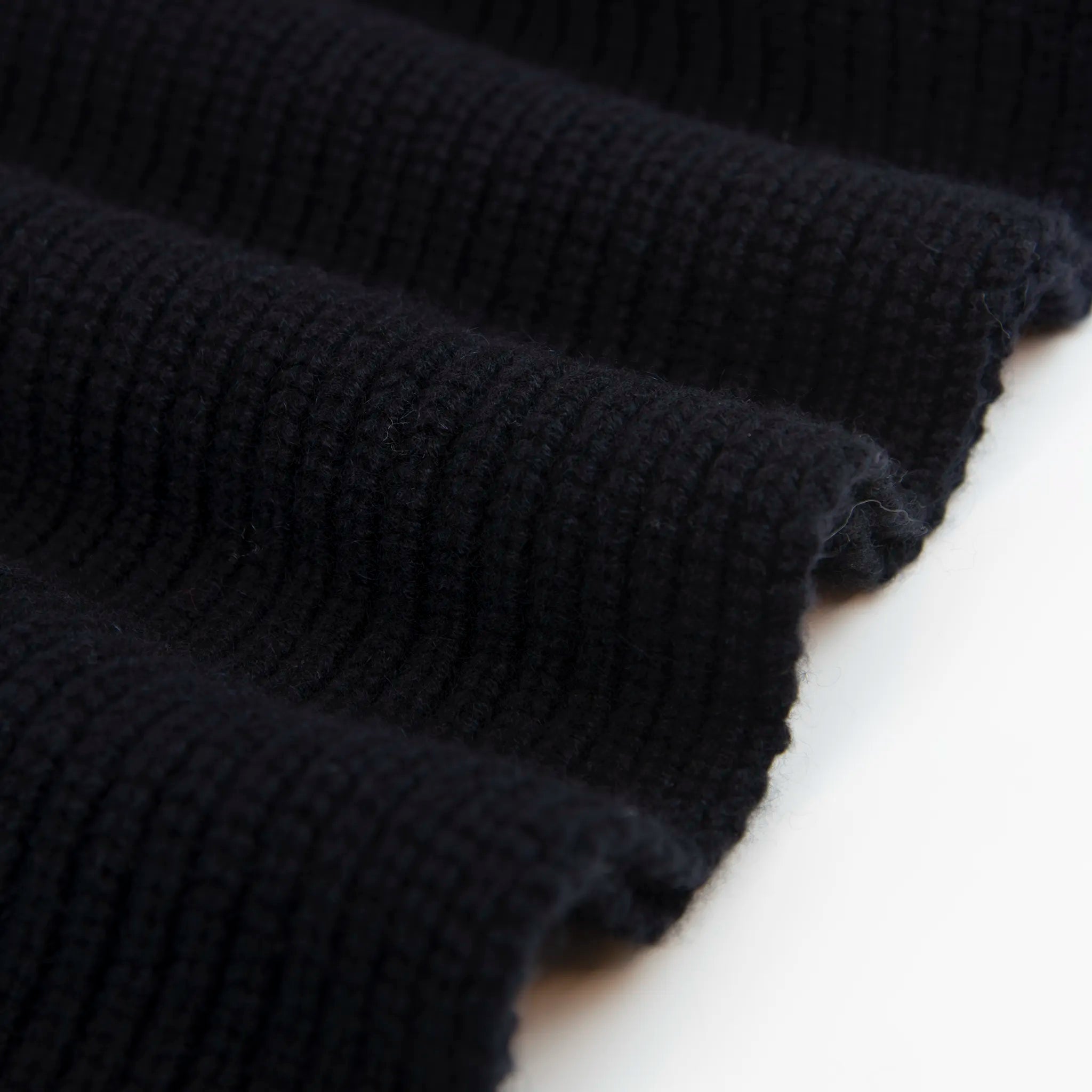 Dettaglio e texture tessuto della sciarpa in 100% cashmere nera, Made in Italy, realizzata su telai antichi con trama a nodo perlato. La morbidezza eccezionale e l'effetto compatto e voluminoso della texture conferiscono al filato un calore avvolgente, ideale per le stagioni più fredde. Un accessorio di alta qualità che unisce eleganza e comfort, perfetto per aggiungere un tocco di lusso al tuo look.