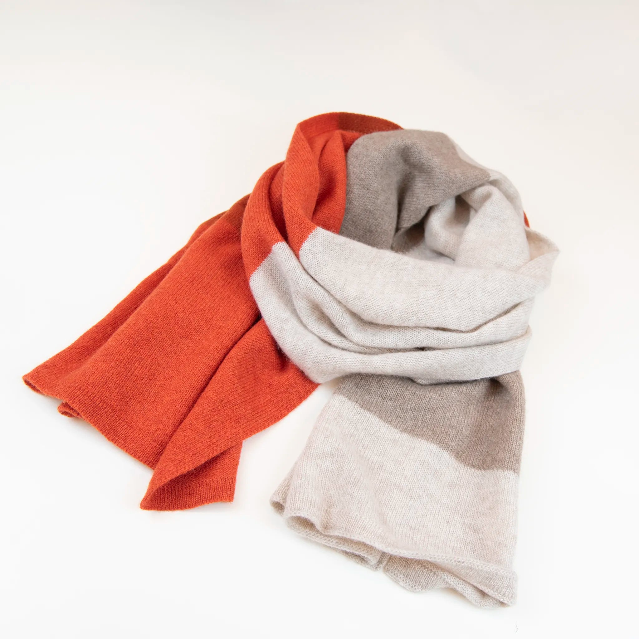 Sciarpa in maglia 100% cashmere arancio e beige, Made in Italy, realizzata su antichi telai. Grazie alla sua ampiezza, può essere utilizzata anche come stola. La pregiata fibra di cashmere offre un'eccezionale finezza e qualità termoisolanti, assicurando calore, protezione e leggerezza in tutte le stagioni. Un accessorio versatile, frutto della creatività di designer specializzati, che aggiunge eleganza e comfort al tuo look.