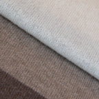 Dettaglio e texture tessuto della sciarpa in maglia 100% cashmere senape, beige e marrone, Made in Italy, realizzata su antichi telai. Grazie alla sua ampiezza, può essere utilizzata anche come stola. La pregiata fibra di cashmere offre un'eccezionale finezza e qualità termoisolanti, assicurando calore, protezione e leggerezza in tutte le stagioni. Un accessorio versatile, frutto della creatività di designer specializzati, che aggiunge eleganza e comfort al tuo look.