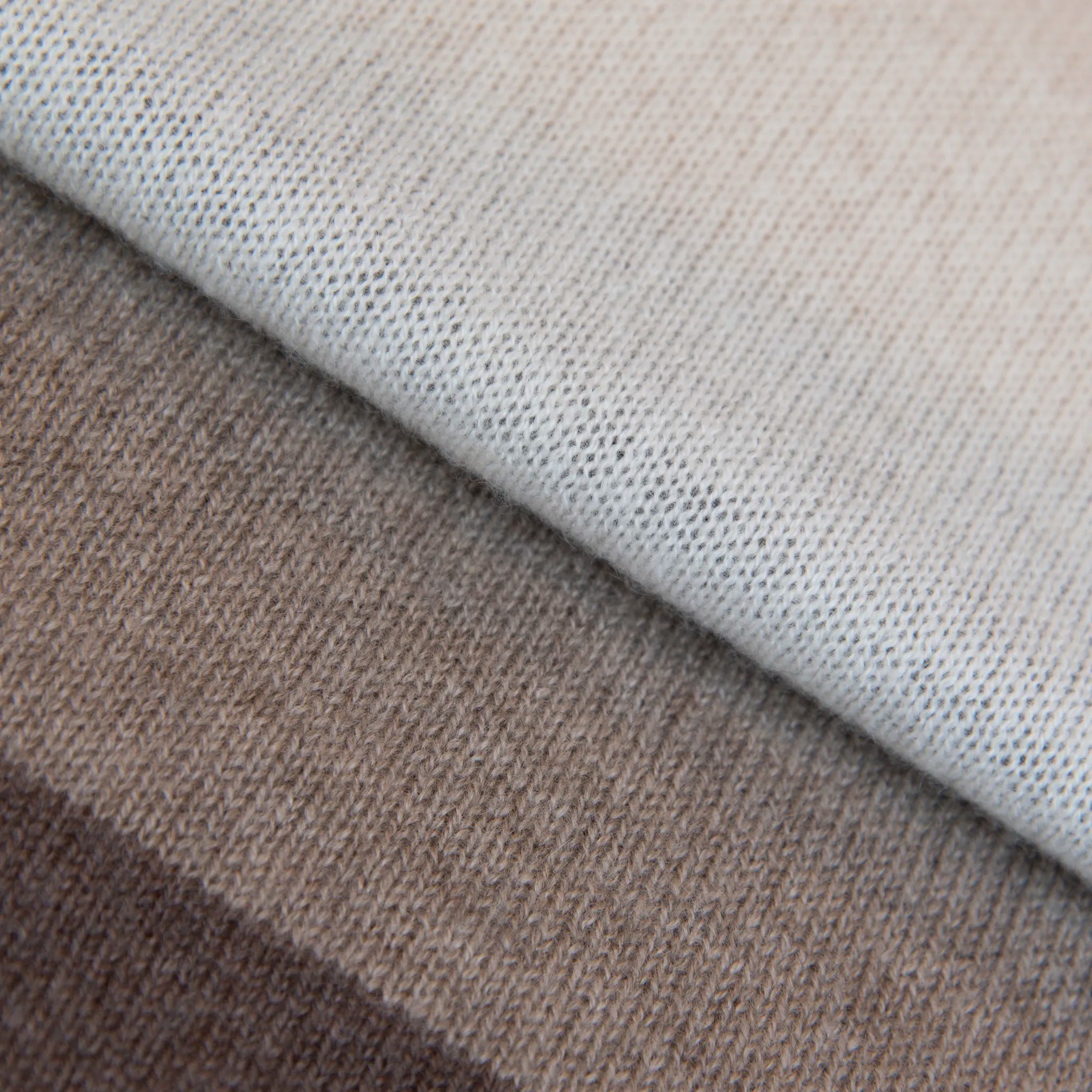 Dettaglio e texture tessuto della sciarpa in maglia 100% cashmere senape, beige e marrone, Made in Italy, realizzata su antichi telai. Grazie alla sua ampiezza, può essere utilizzata anche come stola. La pregiata fibra di cashmere offre un'eccezionale finezza e qualità termoisolanti, assicurando calore, protezione e leggerezza in tutte le stagioni. Un accessorio versatile, frutto della creatività di designer specializzati, che aggiunge eleganza e comfort al tuo look.
