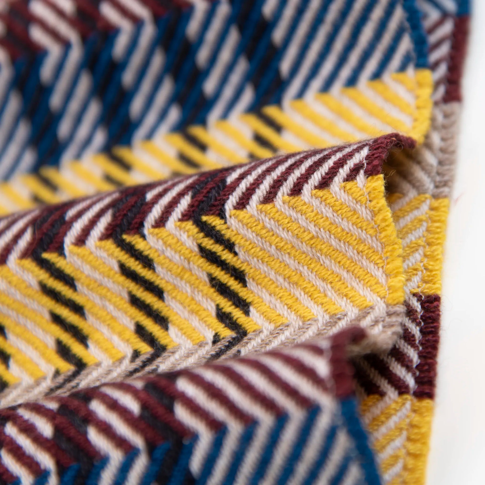 Dettaglio e texture tessuto della sciarpa in cashmere e seta, gialla, marrone, verde, rossa, Made in Italy, con pattern a righe trasversali che dona dinamismo visivo. La fusione armoniosa dei colori rende questa sciarpa facile da abbinare in ogni occasione, offrendo una sensazione di morbidezza, calore e leggerezza. Un accessorio raffinato, frutto della creatività di designer esperti, perfetto per ogni look.