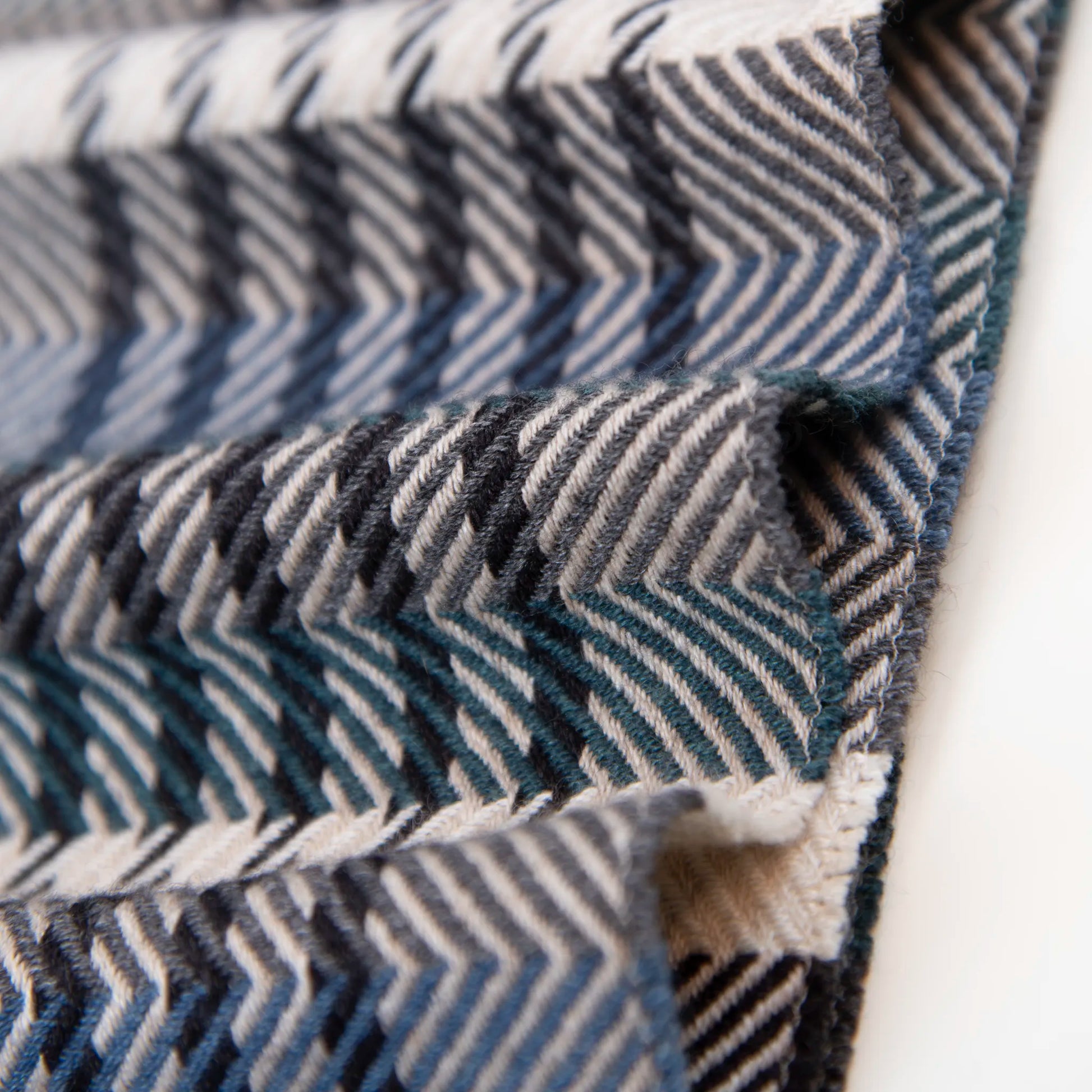 Dettaglio e texture tessuto della sciarpa in cashmere e seta, blu, verde, grigia, Made in Italy, con pattern a righe trasversali che dona dinamismo visivo. La fusione armoniosa dei colori rende questa sciarpa facile da abbinare in ogni occasione, offrendo una sensazione di morbidezza, calore e leggerezza. Un accessorio raffinato, frutto della creatività di designer esperti, perfetto per ogni look.