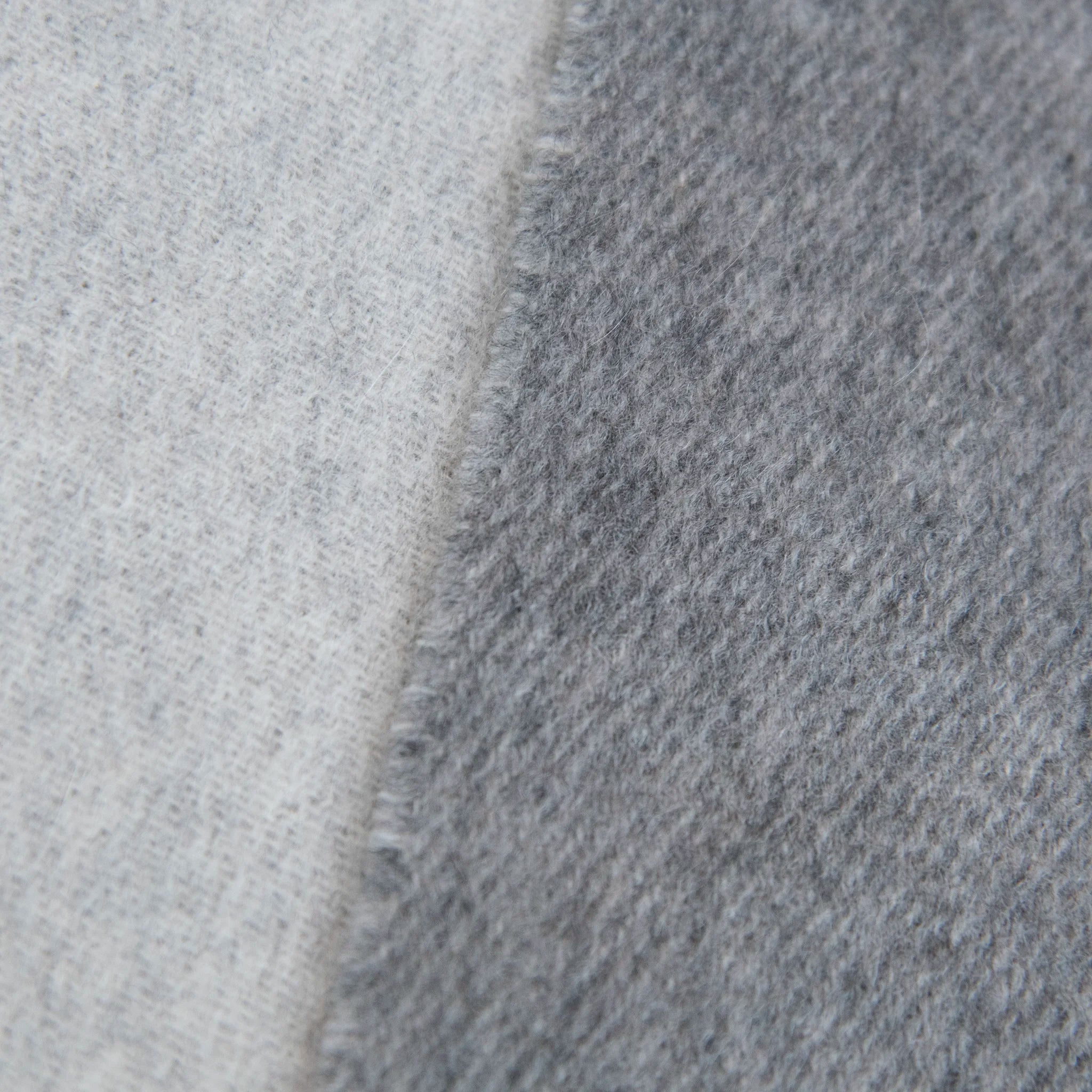 Dettaglio e texture tessutto della sciarpa in doppio panno 100% cashmere, Made in Italy, realizzata su antichi telai che ne esaltano la qualità e la durata nel tempo. Le tonalità chiare di grigio donano luminosità, valorizzando ogni outfit. Morbida e avvolgente, offre una sensazione delicata e confortevole al tatto.
