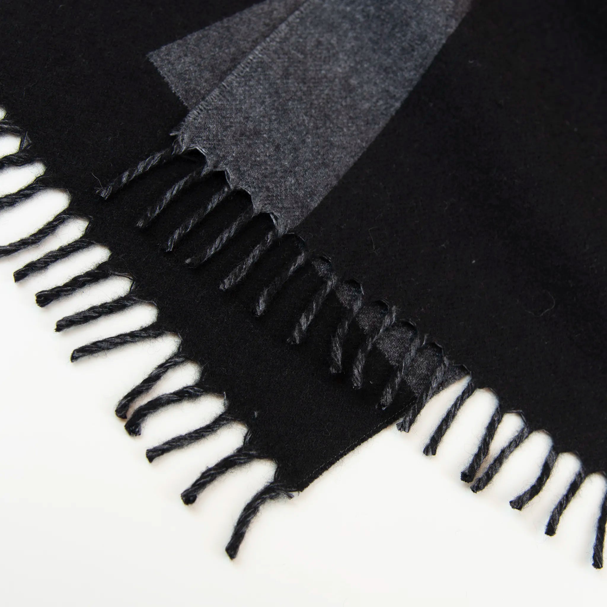 Dettaglio e texture tessuto della sciarpa in cashmere e seta nera, Made in Italy, con struttura in panno rasato che le conferisce leggerezza unica e morbidezza avvolgente al tatto. Le dimensioni contenute esaltano l’eleganza, rendendola ideale per aggiungere un tocco di raffinatezza a ogni look.