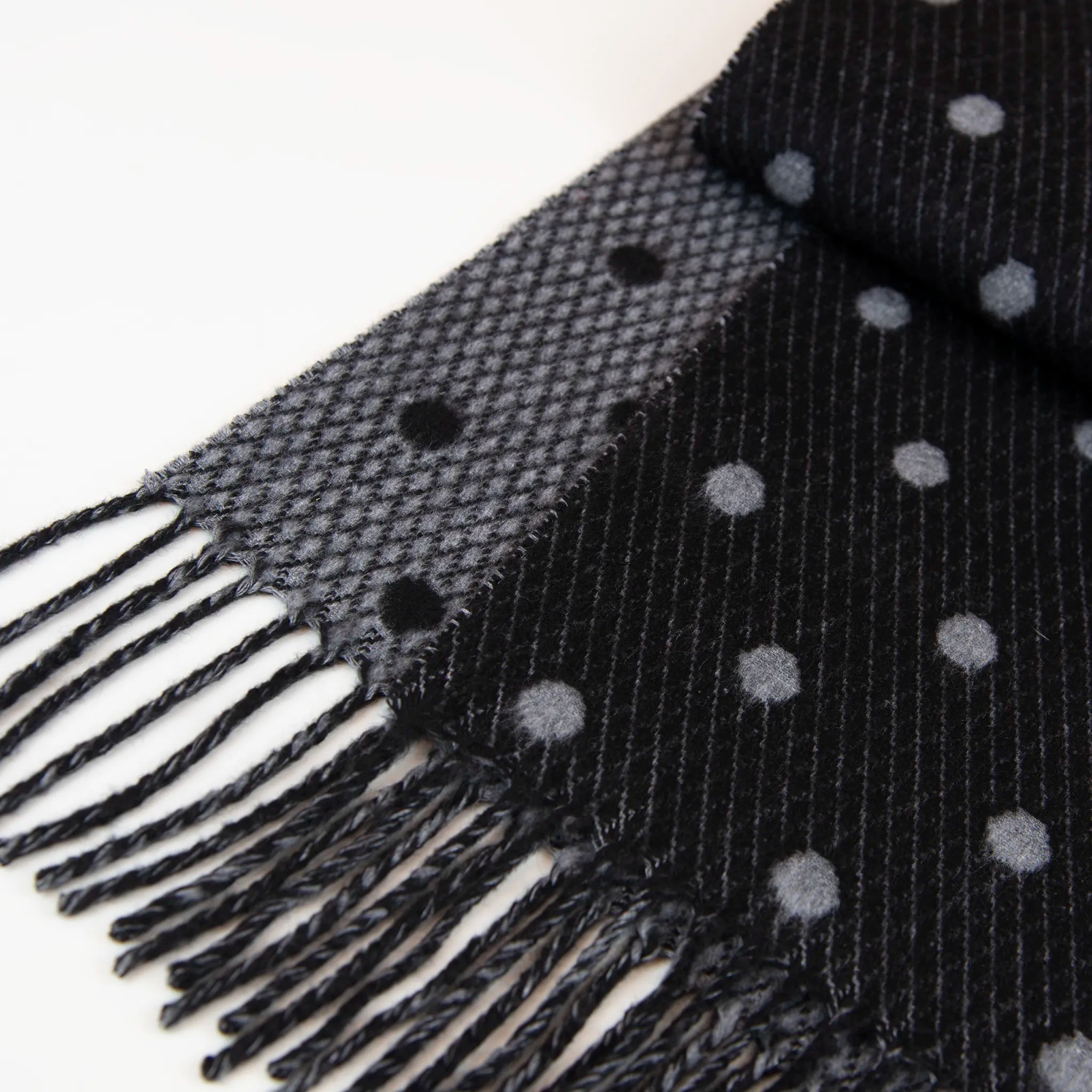 Dettaglio e texture tessuto del Sciarpa in cashmere e seta, nero e grigio, Made in Italy, morbida e calda, con lucentezza naturale della seta. Pattern a pois in negativo sulla parte interna, per una sciarpa versatile, indossabile in due modi diversi.