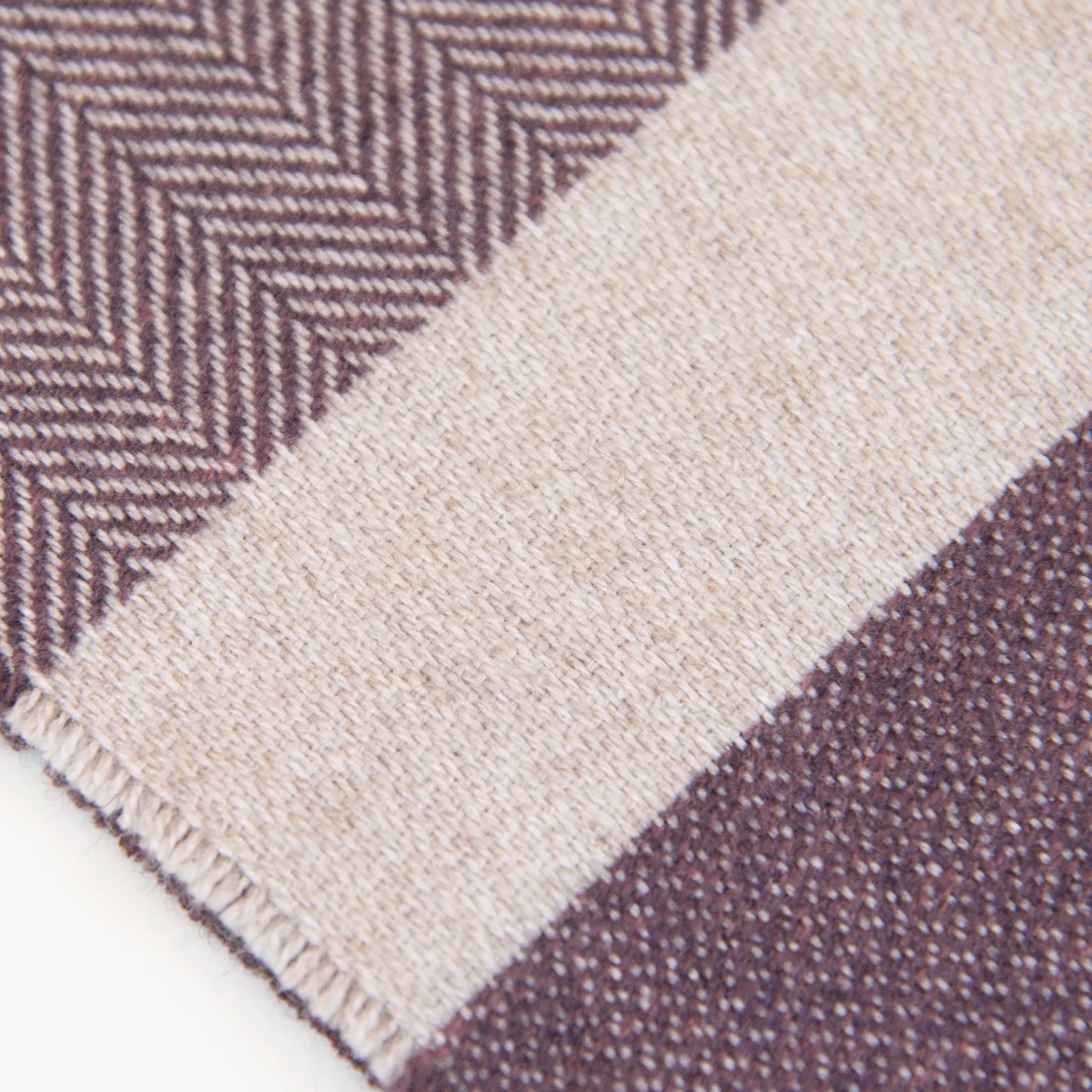 Dettaglio e texture tessuto della sciarpa in cashmere e seta, viola e beige, Made in Italy, con accostamento di due pattern intramontabili: riga e spinato. Curata nei minimi dettagli, offre straordinaria morbidezza e un comfort avvolgente, rendendola un accessorio elegante e versatile.