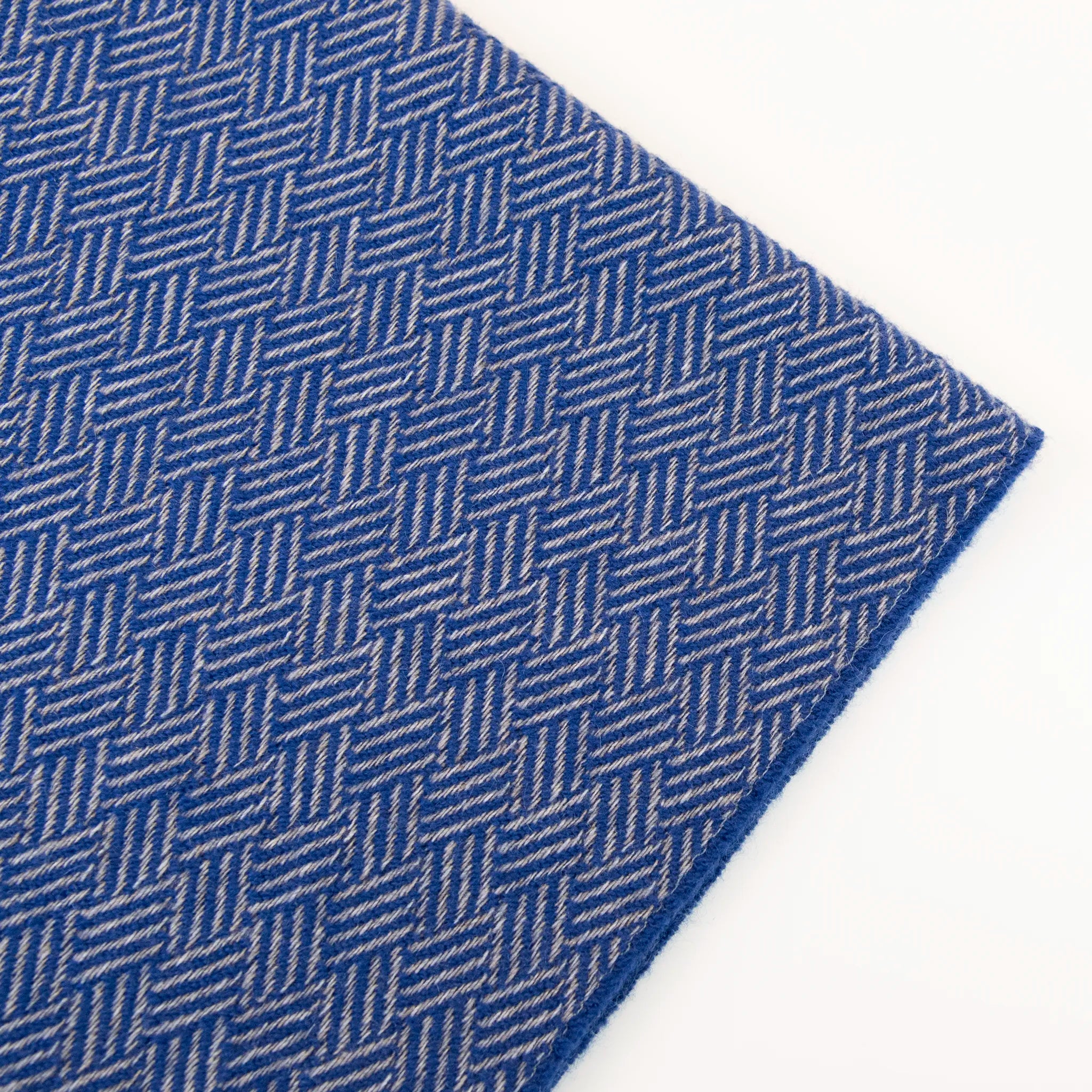 Dettaglio e texture tessuto della Sciarpa in 100% cashmere blu, Made in Italy, con intramontabile pattern ad intreccio e lavorazione leggera in 3D che accentua la percezione al tatto. Il cashmere di alta qualità offre straordinaria finezza, proprietà termoisolanti e garantisce calore, protezione e leggerezza.