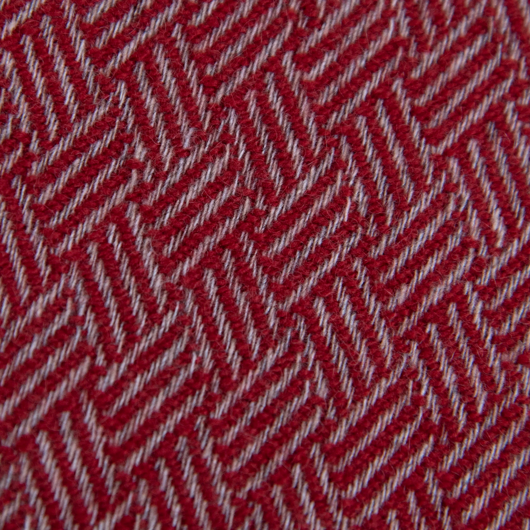 Dettaglio e texture tessuto della Sciarpa in 100% cashmere rossa, Made in Italy, con intramontabile pattern ad intreccio e lavorazione leggera in 3D che accentua la percezione al tatto. Il cashmere di alta qualità offre straordinaria finezza, proprietà termoisolanti e garantisce calore, protezione e leggerezza.