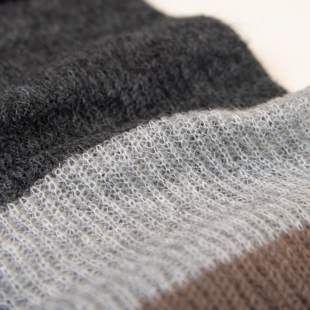 Dettaglio e texture tessuto della sciarpa in lana mohair, marrone, Made in Italy, realizzata nel più antico lanificio della Calabria su telai degli anni '30, garantendo qualità e durata nel tempo. I colori ispirati alla vegetazione dell'Appennino Silano evocano freschezza e vitalità di un paesaggio montano incontaminato. Morbida al tatto, offre una sensazione di sofficità che avvolge delicatamente il corpo, per un comfort senza pari.