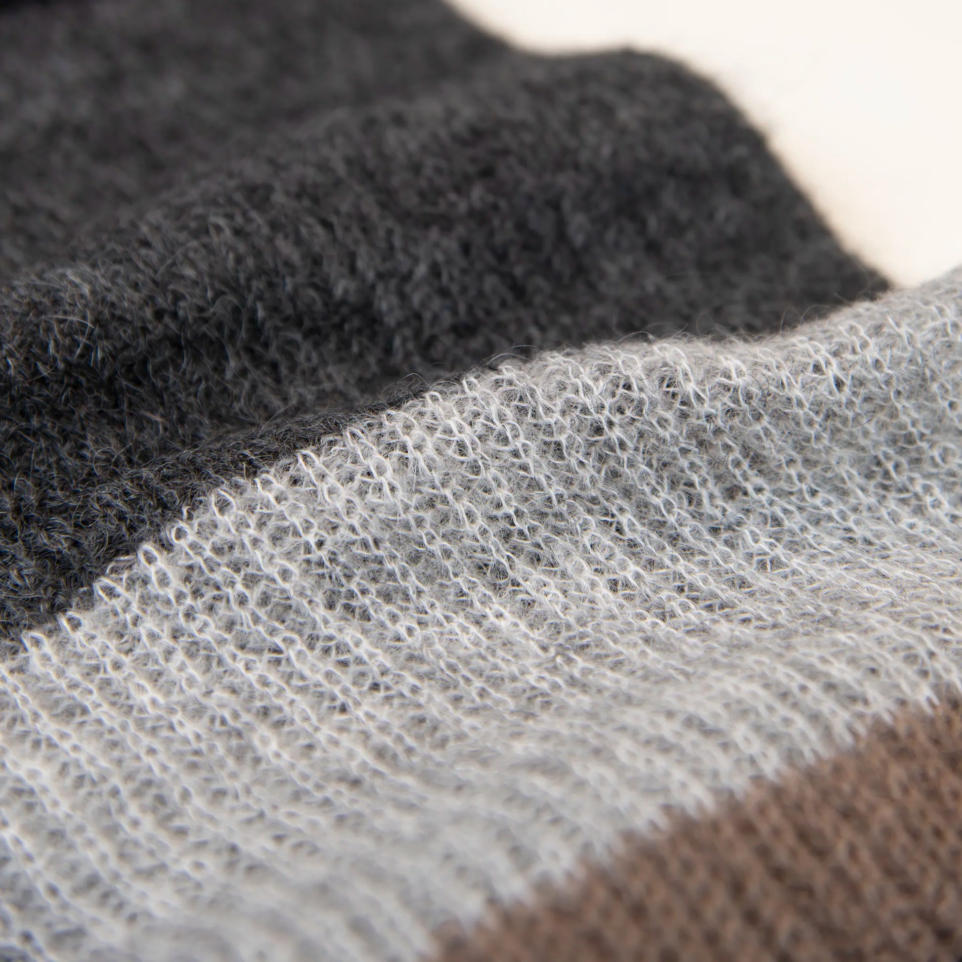 Dettaglio e texture tessuto della sciarpa in lana mohair, marrone, Made in Italy, realizzata nel più antico lanificio della Calabria su telai degli anni '30, garantendo qualità e durata nel tempo. I colori ispirati alla vegetazione dell'Appennino Silano evocano freschezza e vitalità di un paesaggio montano incontaminato. Morbida al tatto, offre una sensazione di sofficità che avvolge delicatamente il corpo, per un comfort senza pari.