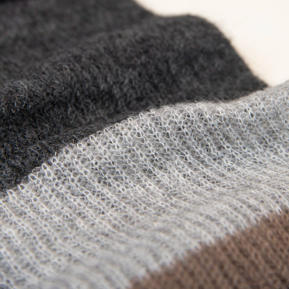 Dettaglio e texture tessuto della sciarpa in lana mohair, marrone, Made in Italy, realizzata nel più antico lanificio della Calabria su telai degli anni '30, garantendo qualità e durata nel tempo. I colori ispirati alla vegetazione dell'Appennino Silano evocano freschezza e vitalità di un paesaggio montano incontaminato. Morbida al tatto, offre una sensazione di sofficità che avvolge delicatamente il corpo, per un comfort senza pari.