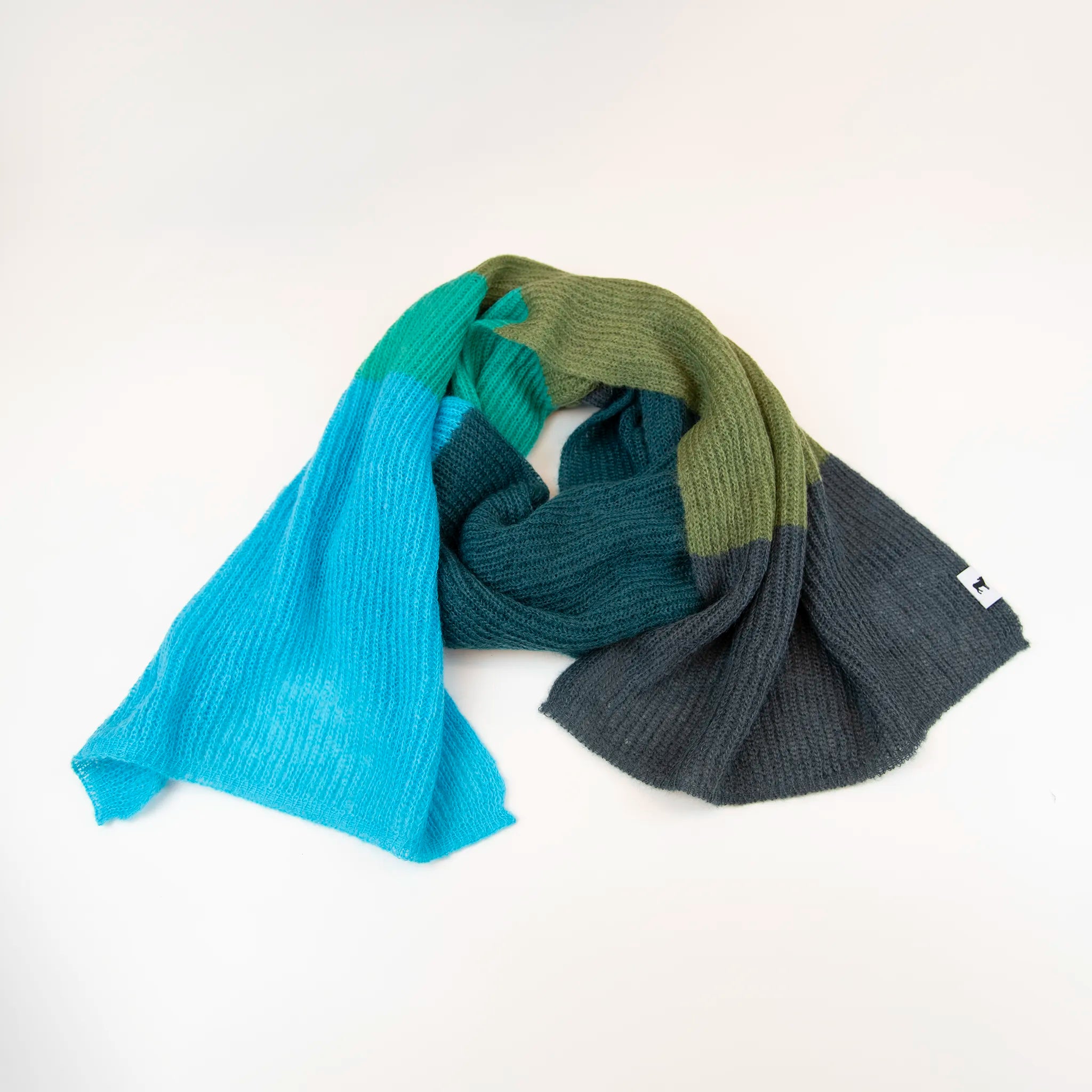 Sciarpa in lana mohair, verde,  Made in Italy, realizzata nel più antico lanificio della Calabria su telai degli anni '30, garantendo qualità e durata nel tempo. I colori ispirati al sottobosco autunnale dell'Appennino Silano evocano la quiete e la bellezza dei paesaggi autunnali. Morbida al tatto, offre una sensazione di sofficità che avvolge delicatamente il corpo, per un comfort senza pari.