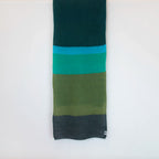 Sciarpa in lana mohair, verde,  Made in Italy, realizzata nel più antico lanificio della Calabria su telai degli anni '30, garantendo qualità e durata nel tempo. I colori ispirati al sottobosco autunnale dell'Appennino Silano evocano la quiete e la bellezza dei paesaggi autunnali. Morbida al tatto, offre una sensazione di sofficità che avvolge delicatamente il corpo, per un comfort senza pari.