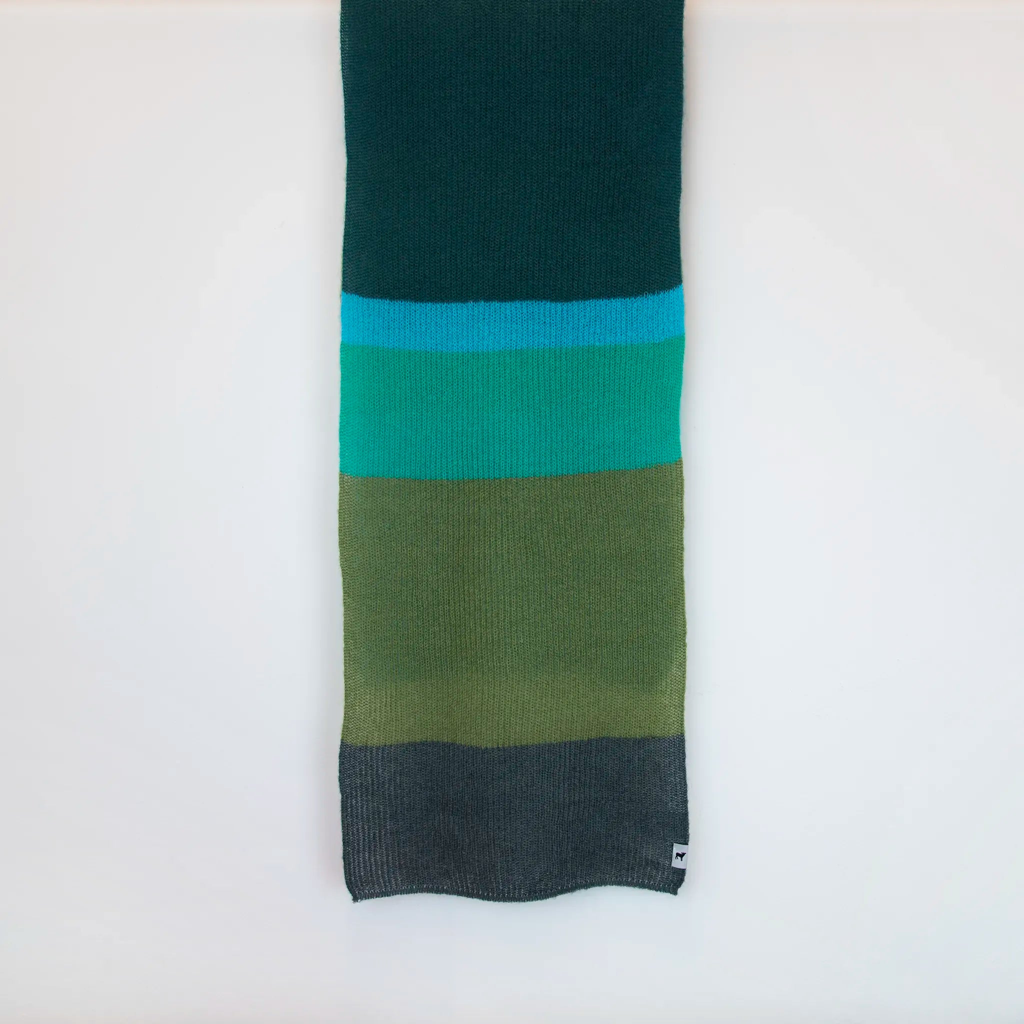 Sciarpa in lana mohair, verde,  Made in Italy, realizzata nel più antico lanificio della Calabria su telai degli anni '30, garantendo qualità e durata nel tempo. I colori ispirati al sottobosco autunnale dell'Appennino Silano evocano la quiete e la bellezza dei paesaggi autunnali. Morbida al tatto, offre una sensazione di sofficità che avvolge delicatamente il corpo, per un comfort senza pari.